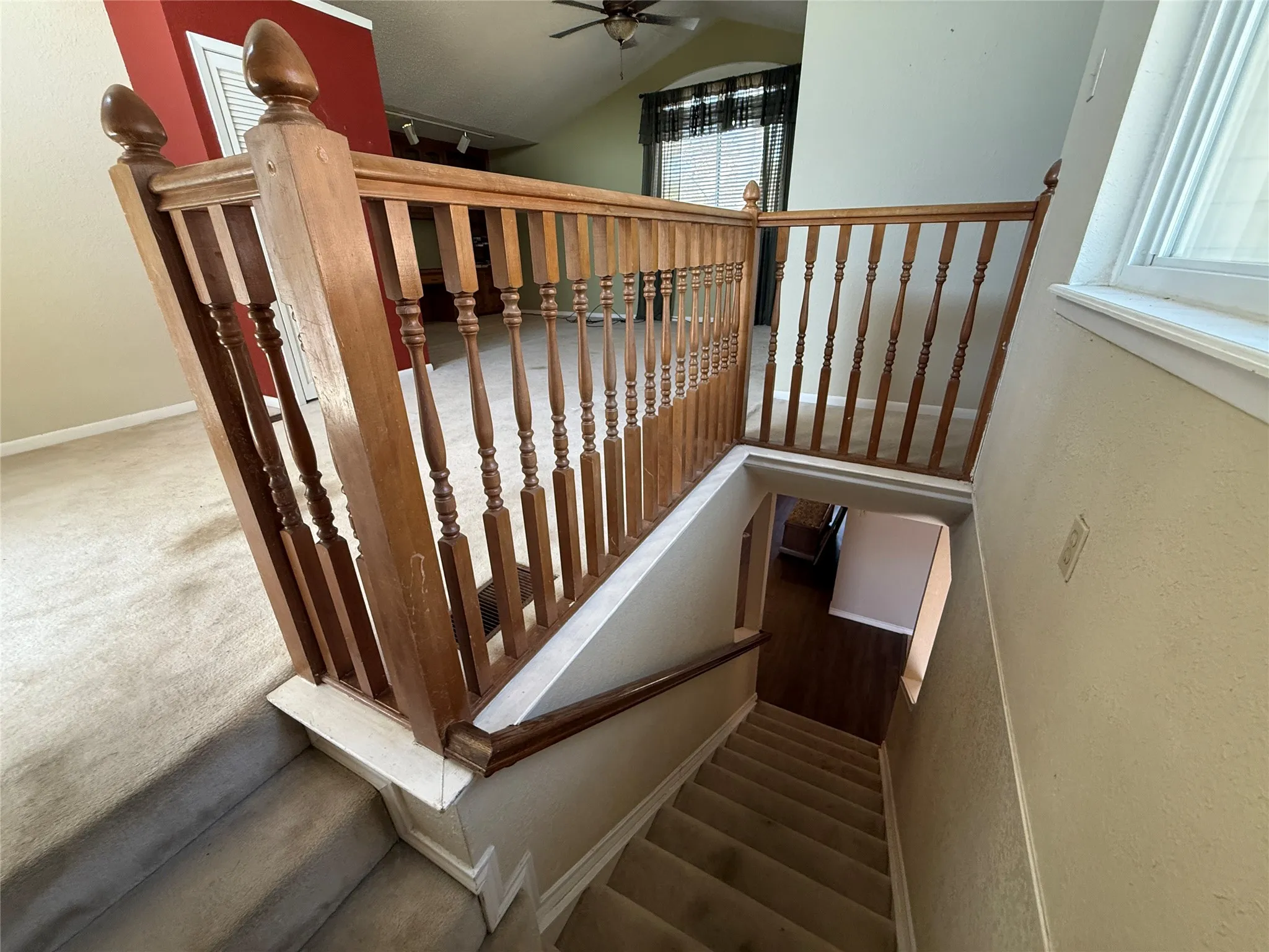Staircase featuring wood balusters and handrail, carpeted treads, and a window providing natural light