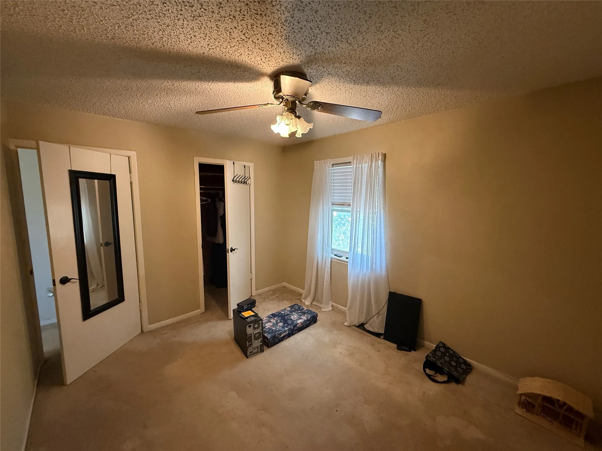 Carpeted room with a ceiling fan, a window with blinds, and two doorways