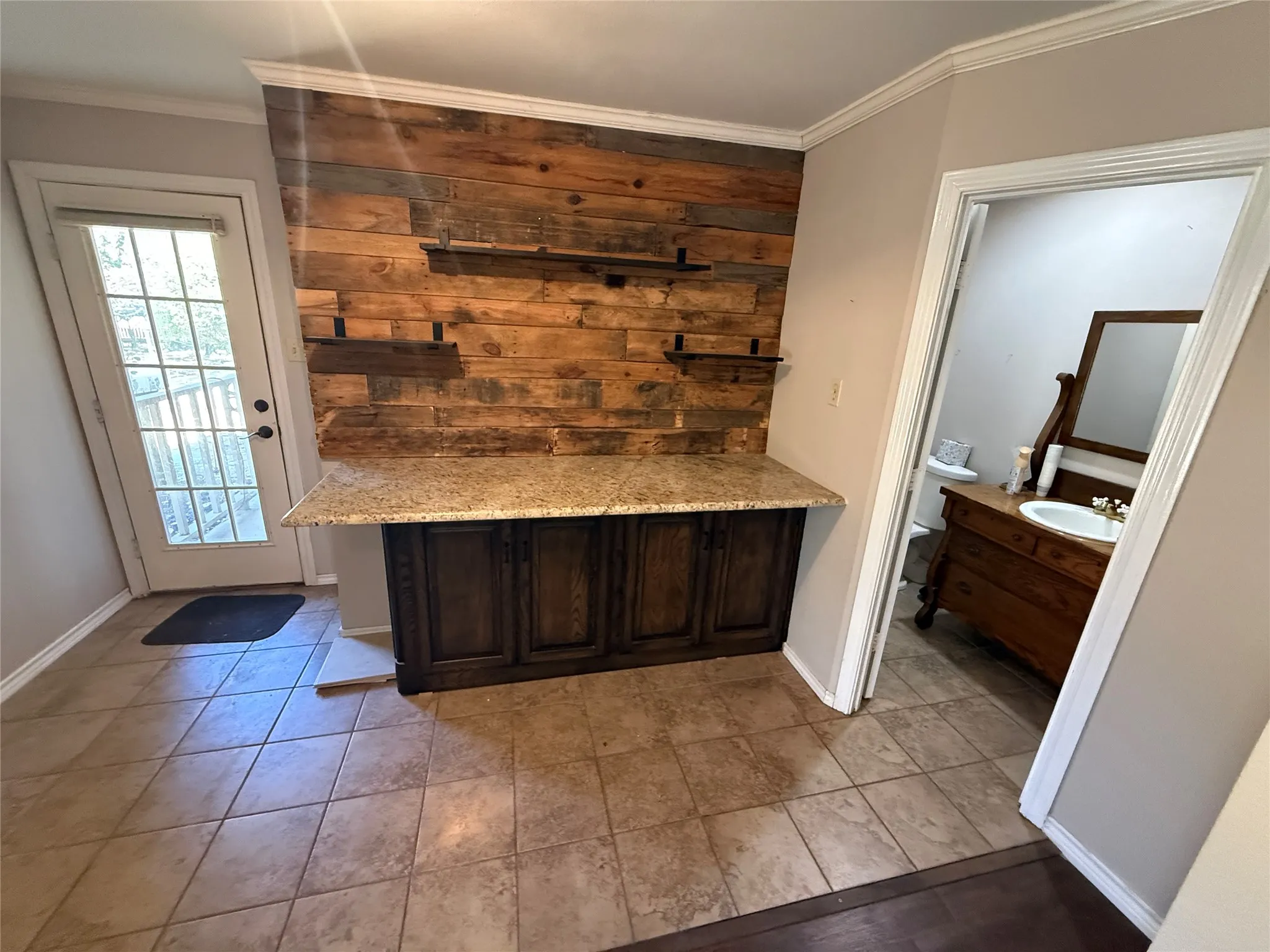 Built-in cabinetry with a granite countertop, wood-plank accent wall, and ceramic tile flooring