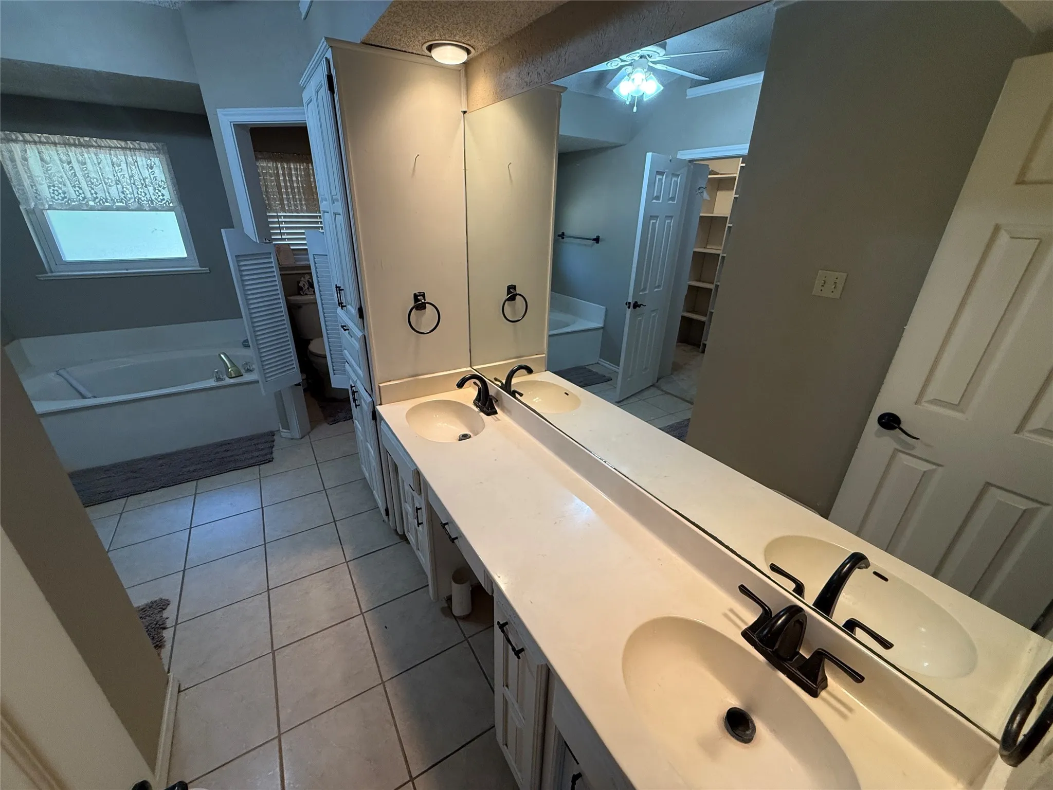 Dual vanity with black hardware, integrated sinks, white cabinetry, and overhead lighting