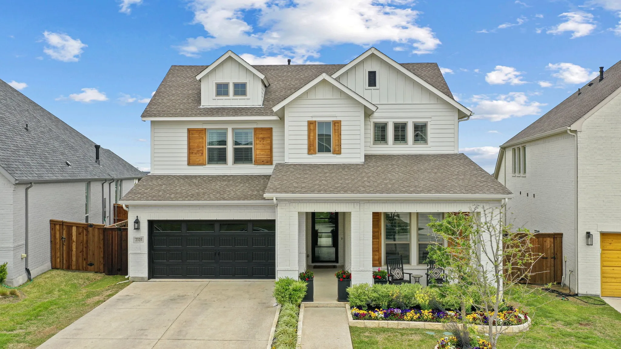 Modern farmhouse exterior with white siding, dark shingle roof, and wooden shutters