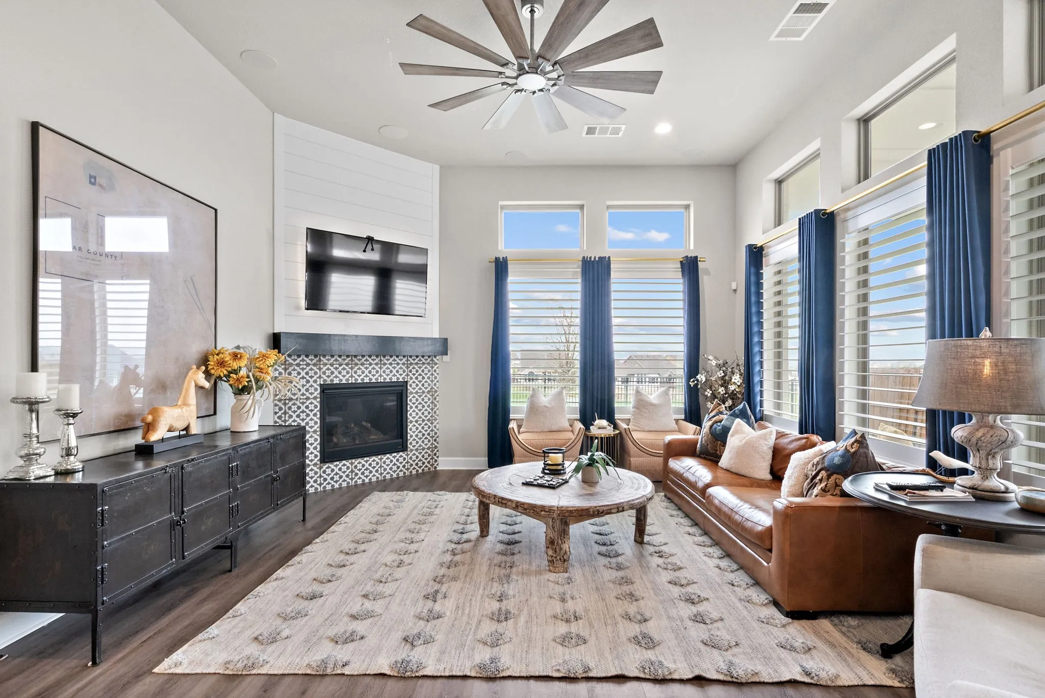 Spacious living area featuring wood-finish flooring, a contemporary ceiling fan, and a fireplace with mosaic tile surround
