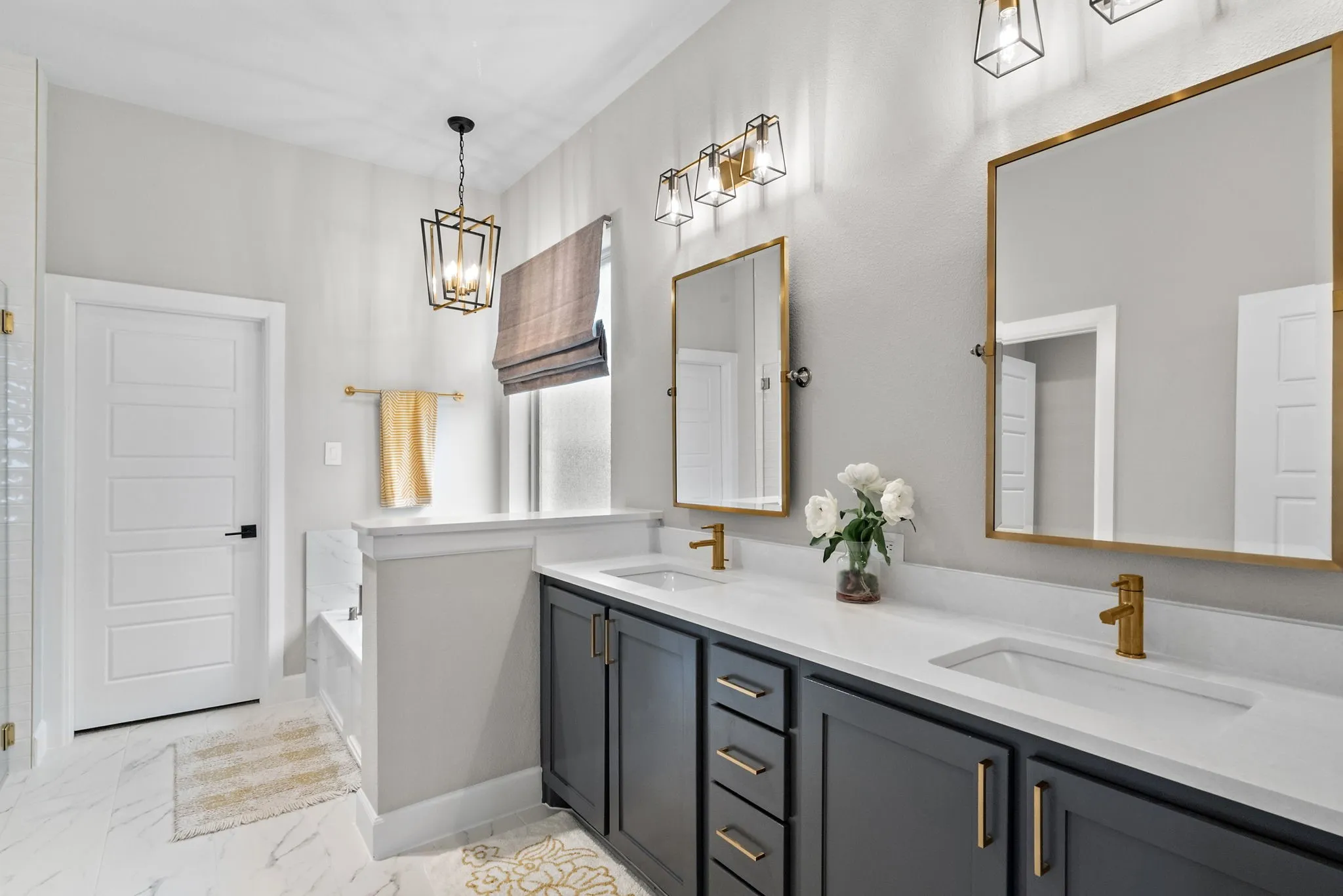 Dual vanities with matte gold fixtures, white countertop, dark cabinetry, and gold-framed mirrors