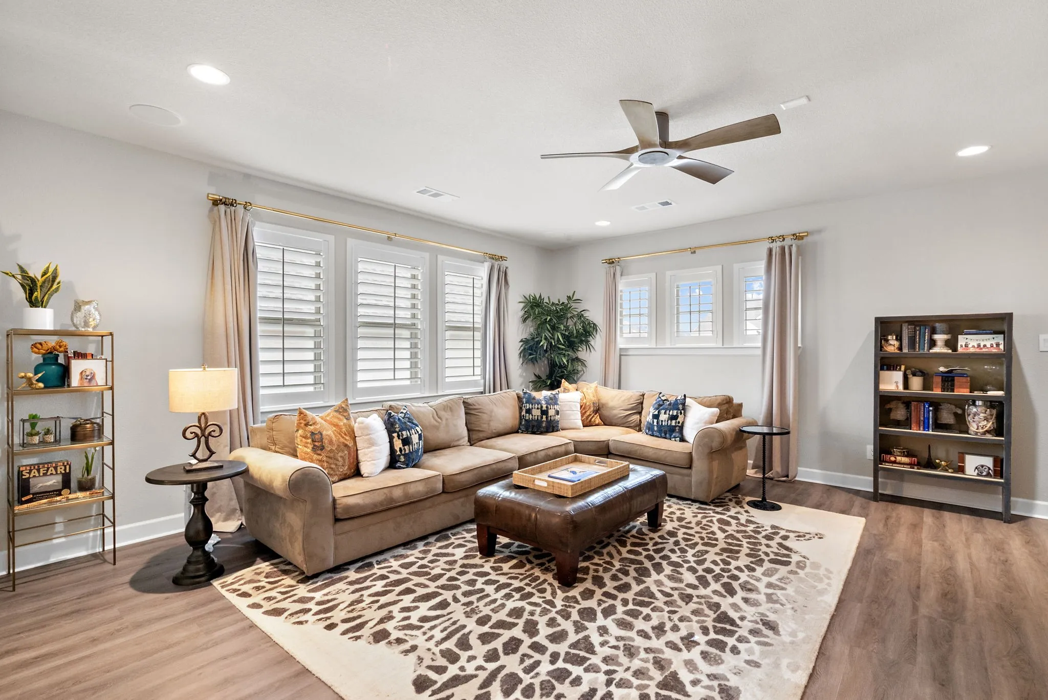 Recessed lighting, ceiling fan, wood-finish flooring, multiple windows with plantation shutters, and light gray wall paint