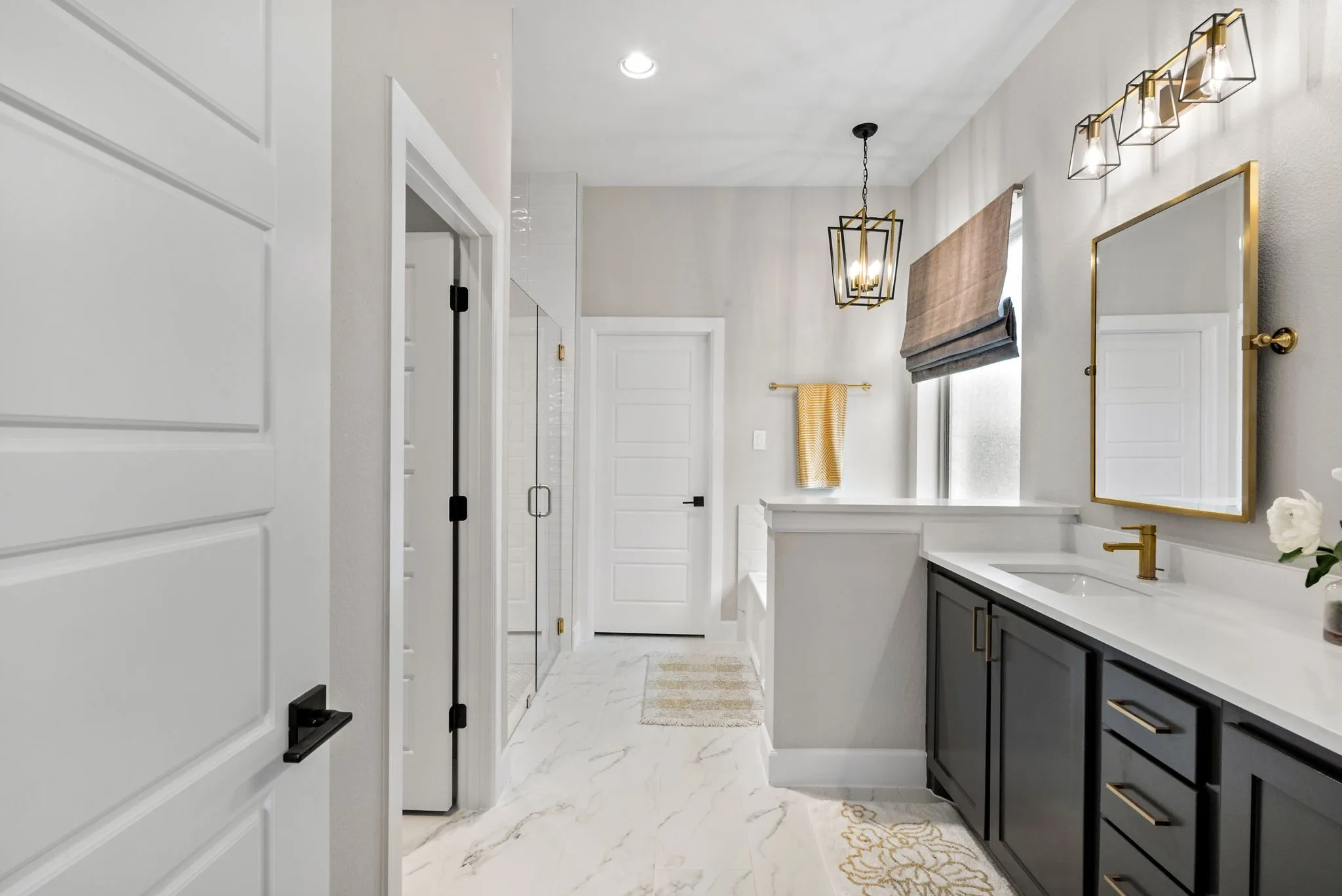 Contemporary bathroom featuring a dark wood-finish vanity with a white countertop, a gold-framed mirror, and a walk-in shower with clear glass enclosure