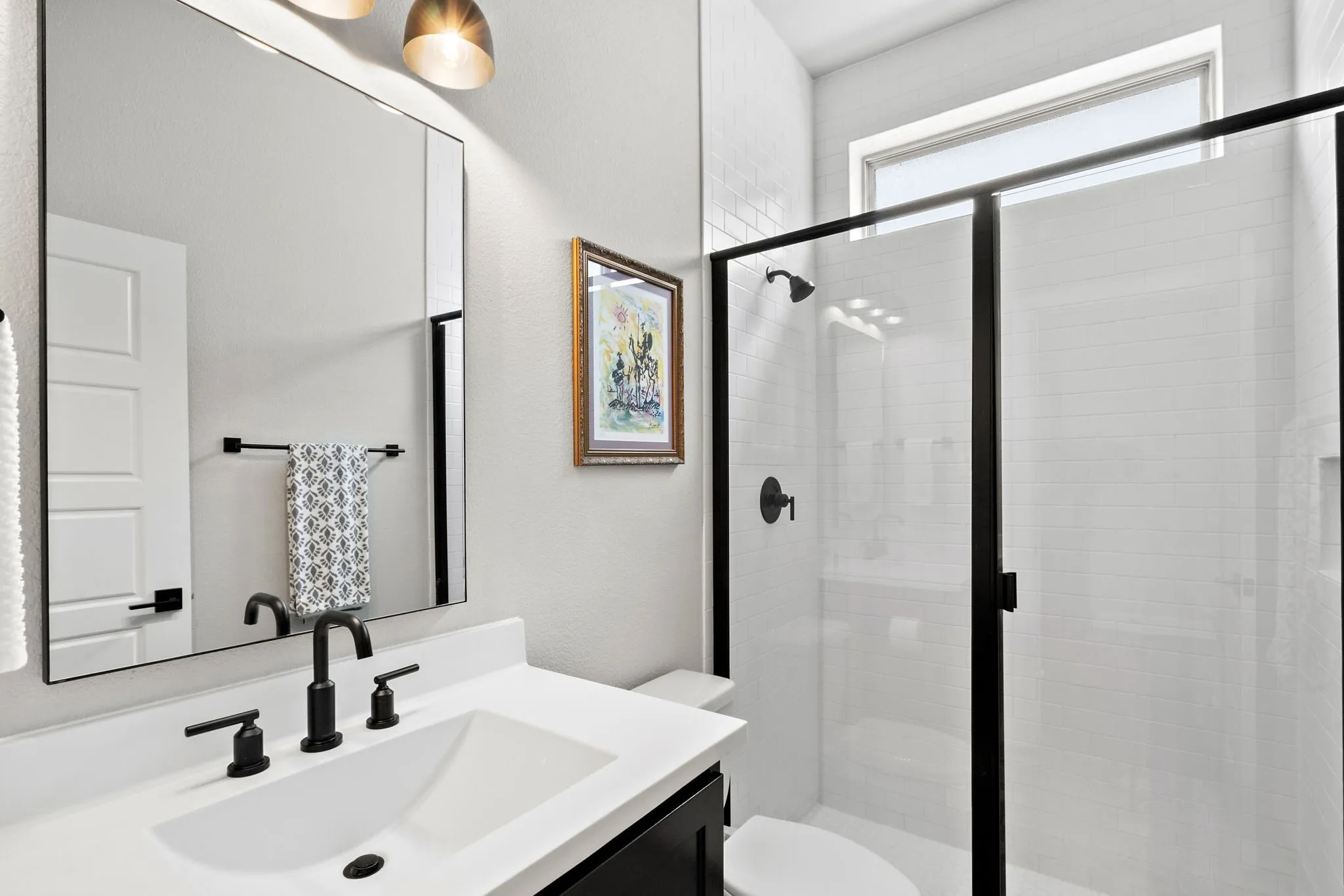 Vanity with integrated sink, matte black faucet, and framed mirror
