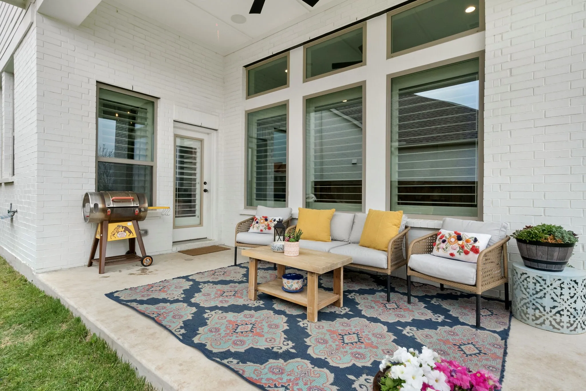 Covered patio featuring a white brick exterior, concrete flooring, and multiple large windows