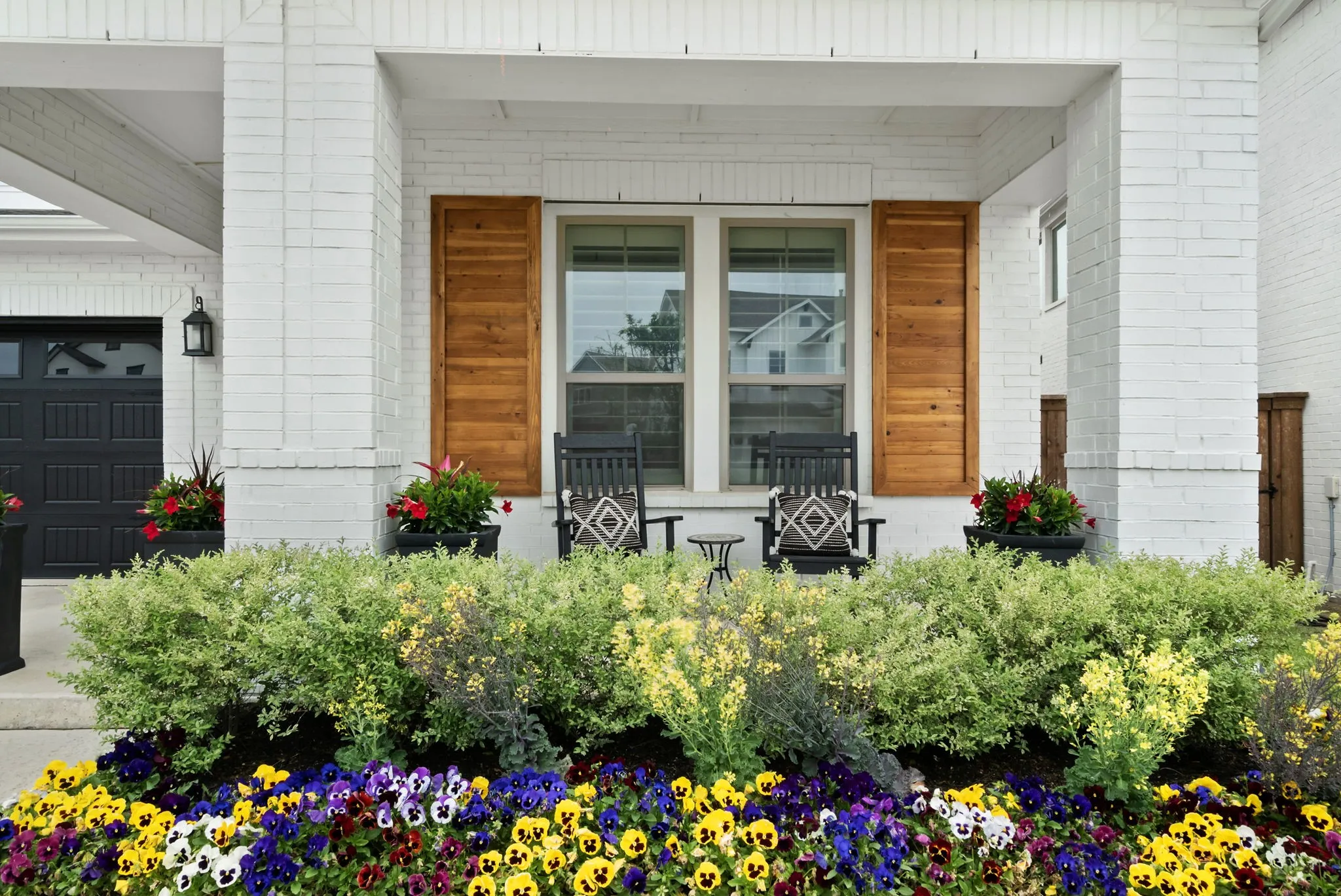 Brick exterior with a covered porch, wood-paneled shutters, and integrated landscaping