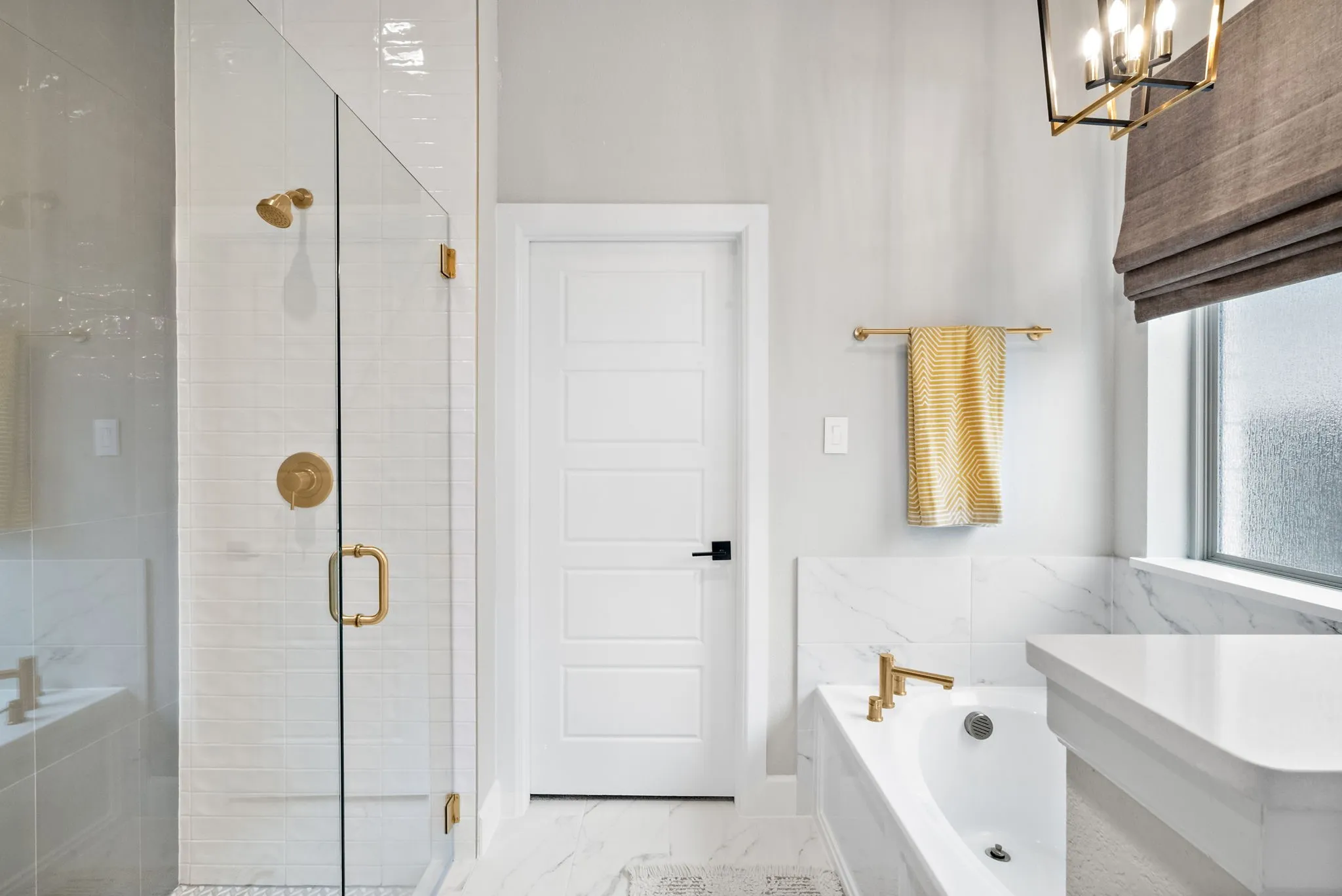 Walk-in shower with clear glass enclosure and gold-finish hardware