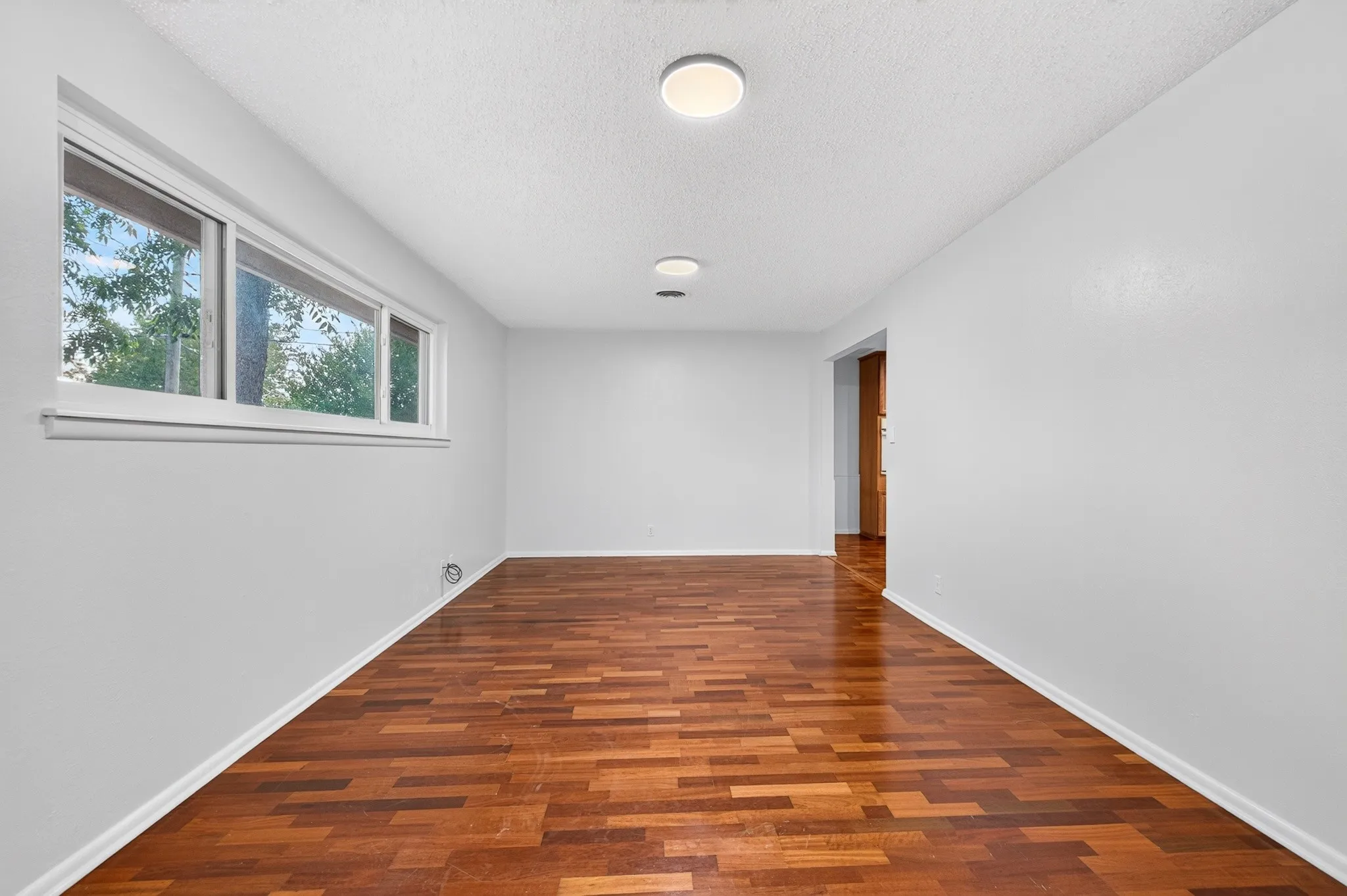 Wood-finish flooring, white walls, white trim, recessed lighting, and a long window