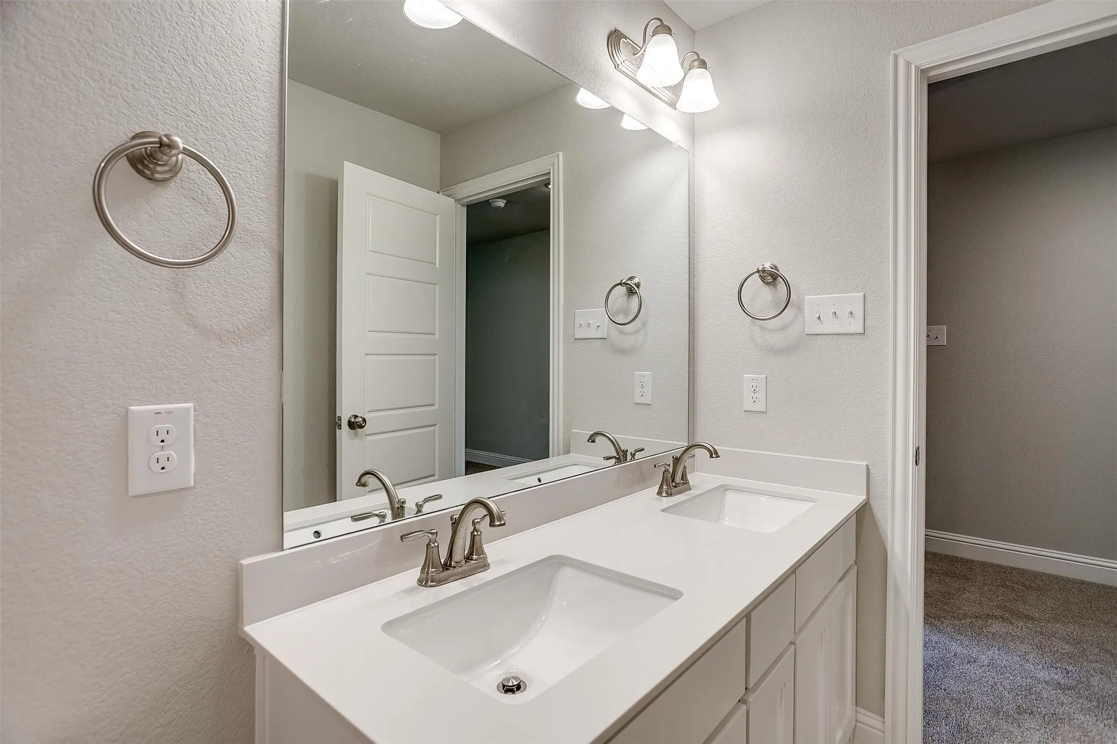Dual vanity with white cabinetry, integrated sinks, brushed nickel faucets, and a full-width mirror