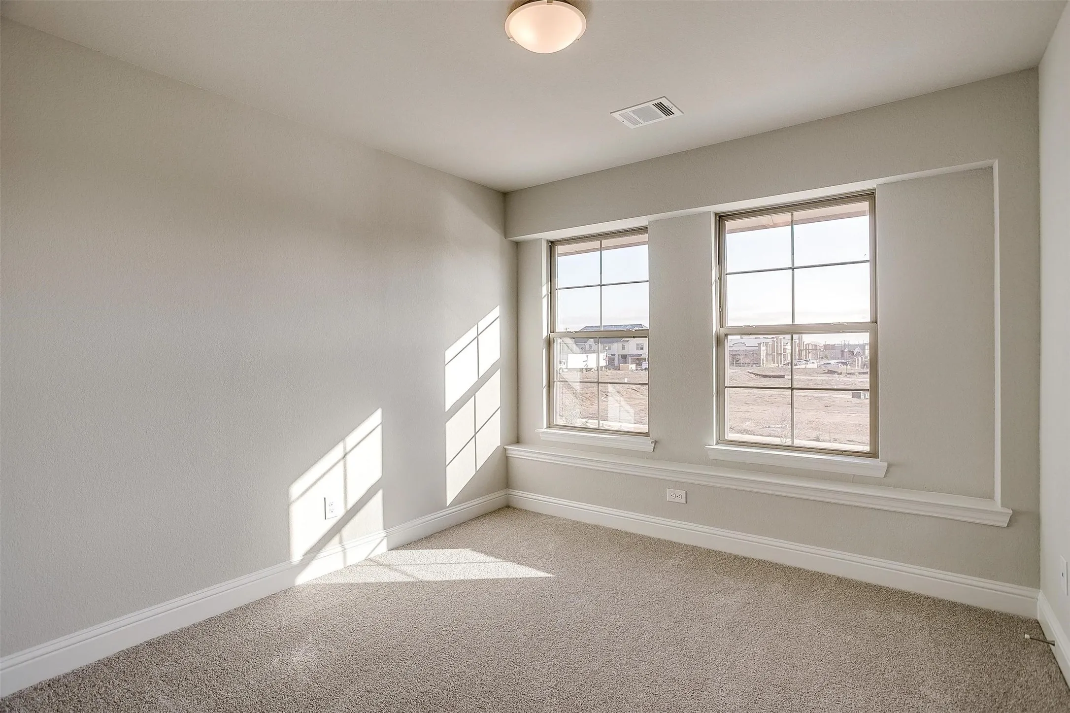 Neutral wall paint, plush carpet flooring, twin pane windows, architectural window trim, and a flush mount ceiling fixture