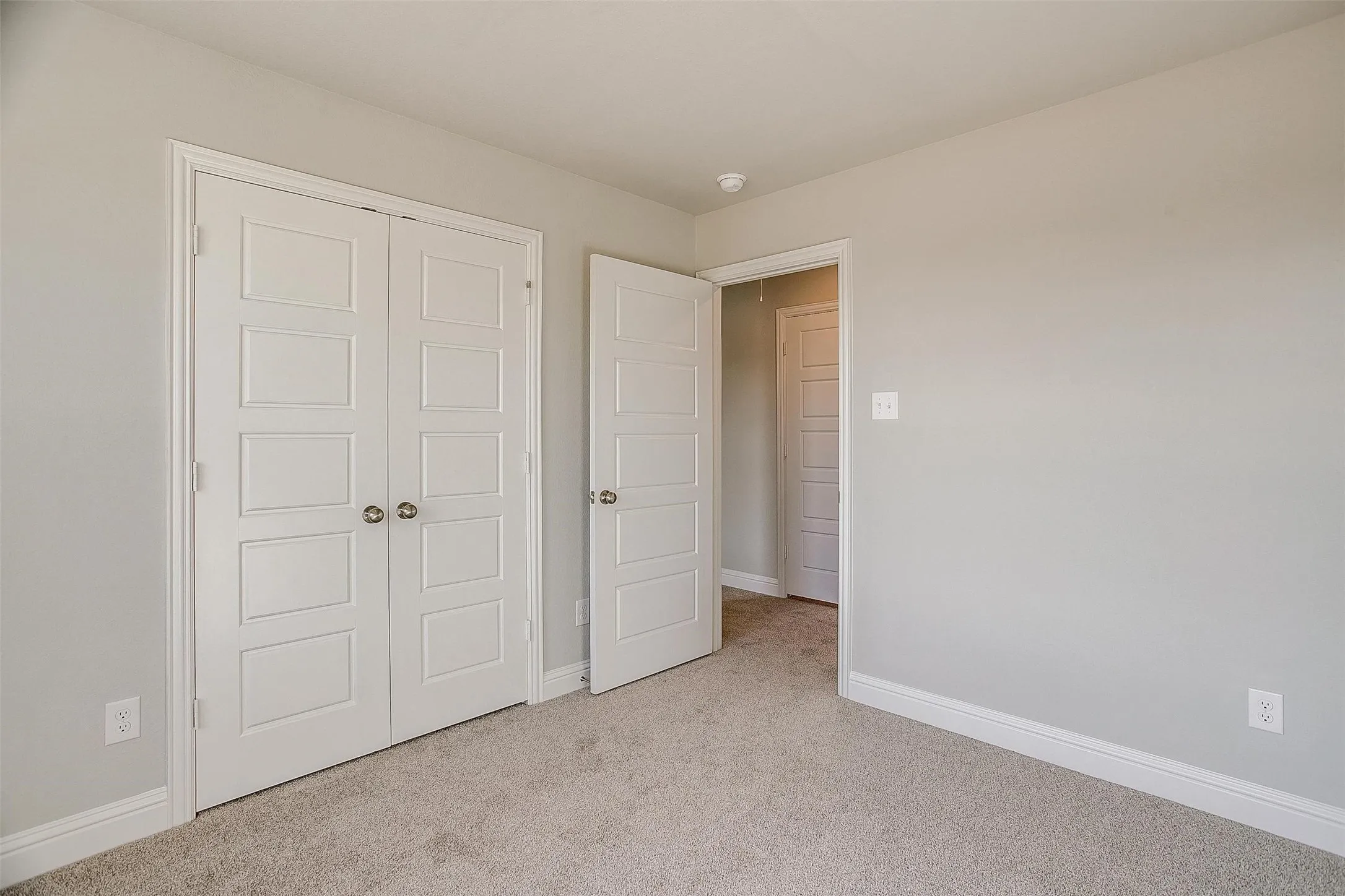 Neutral wall paint, carpet flooring, white trim, and white paneled doors