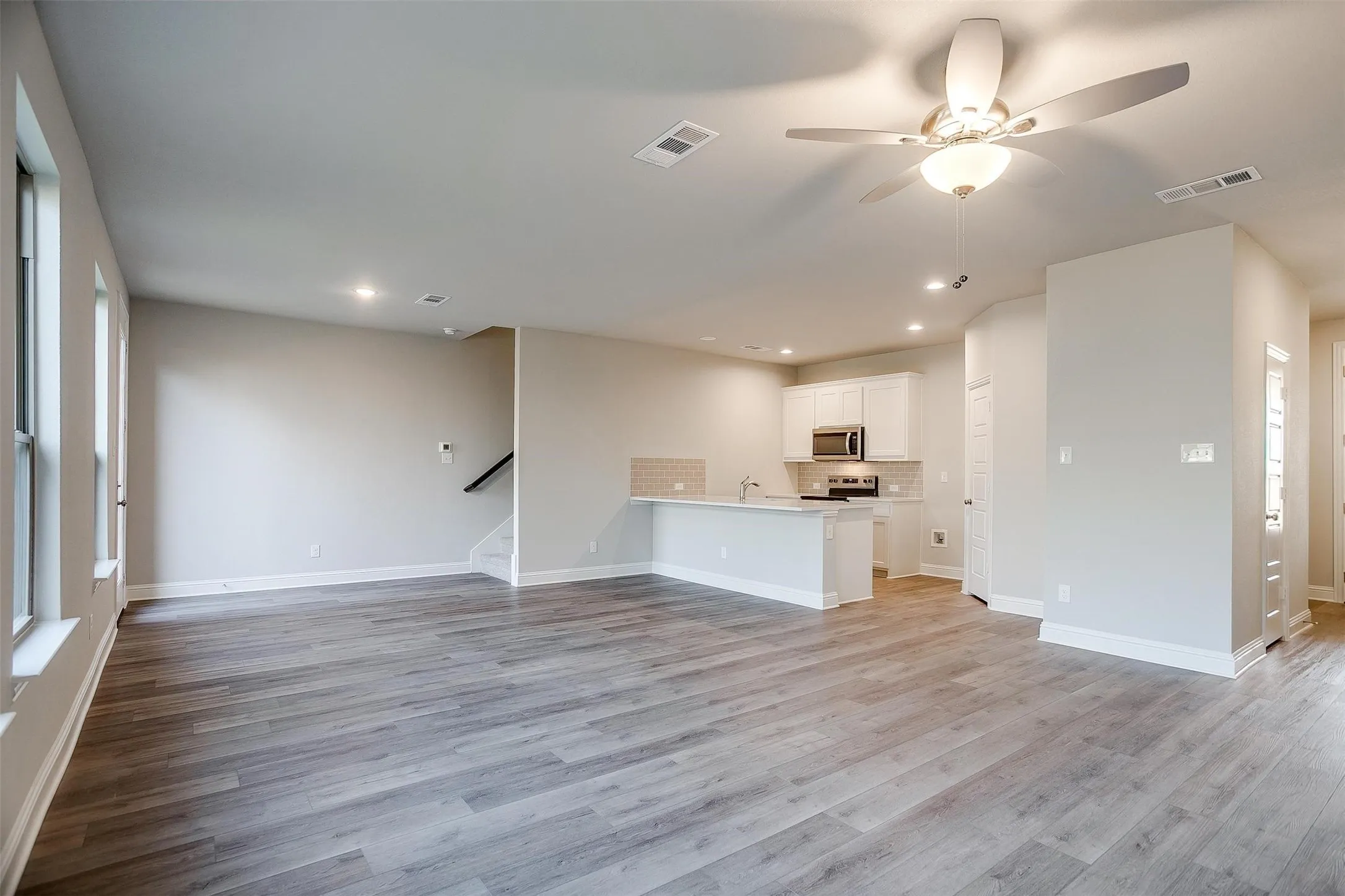 Open-concept living area featuring wood-finish flooring, recessed lighting, and a ceiling fan