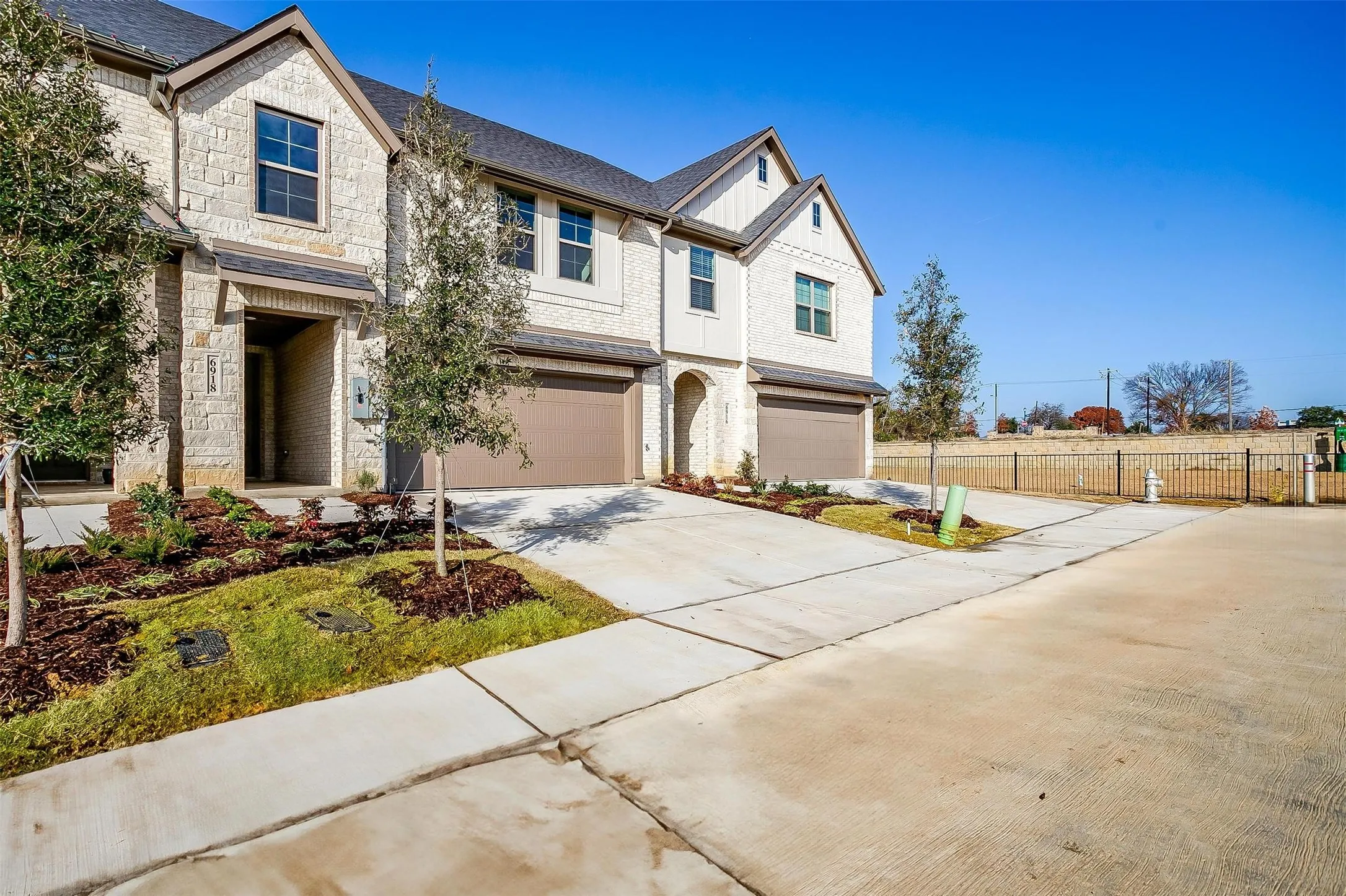 Stone and siding exterior with multiple gables, attached two-car garage, concrete driveway, and landscaped front planting beds