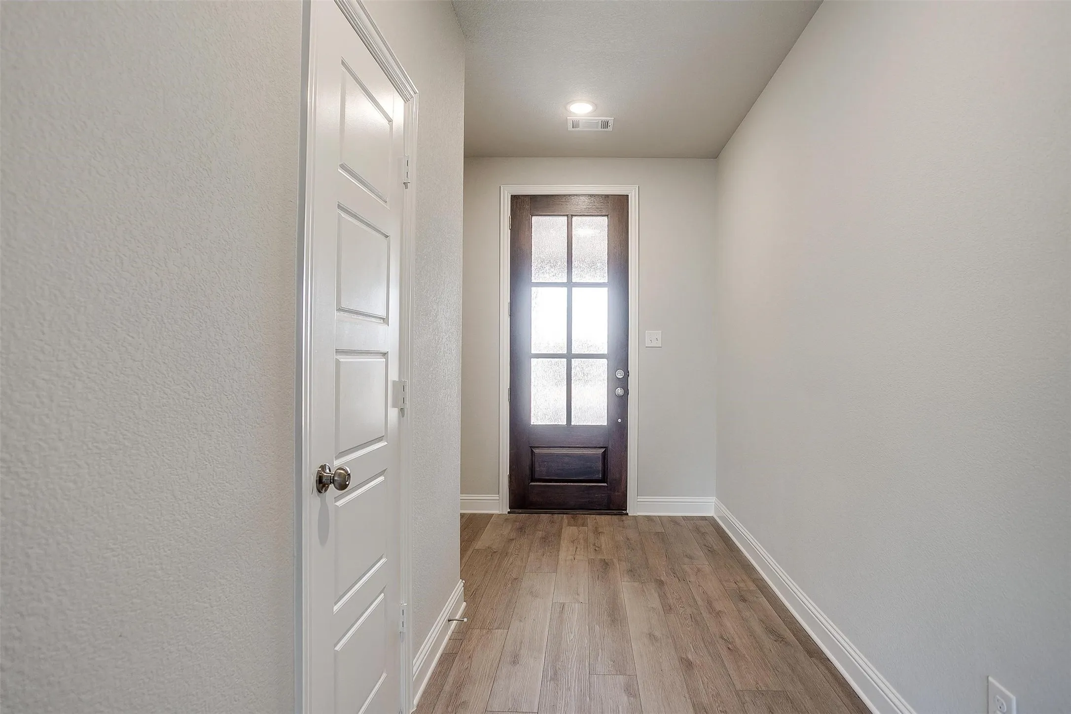 Wood-finish flooring, white trim, recessed lighting, and panel doors