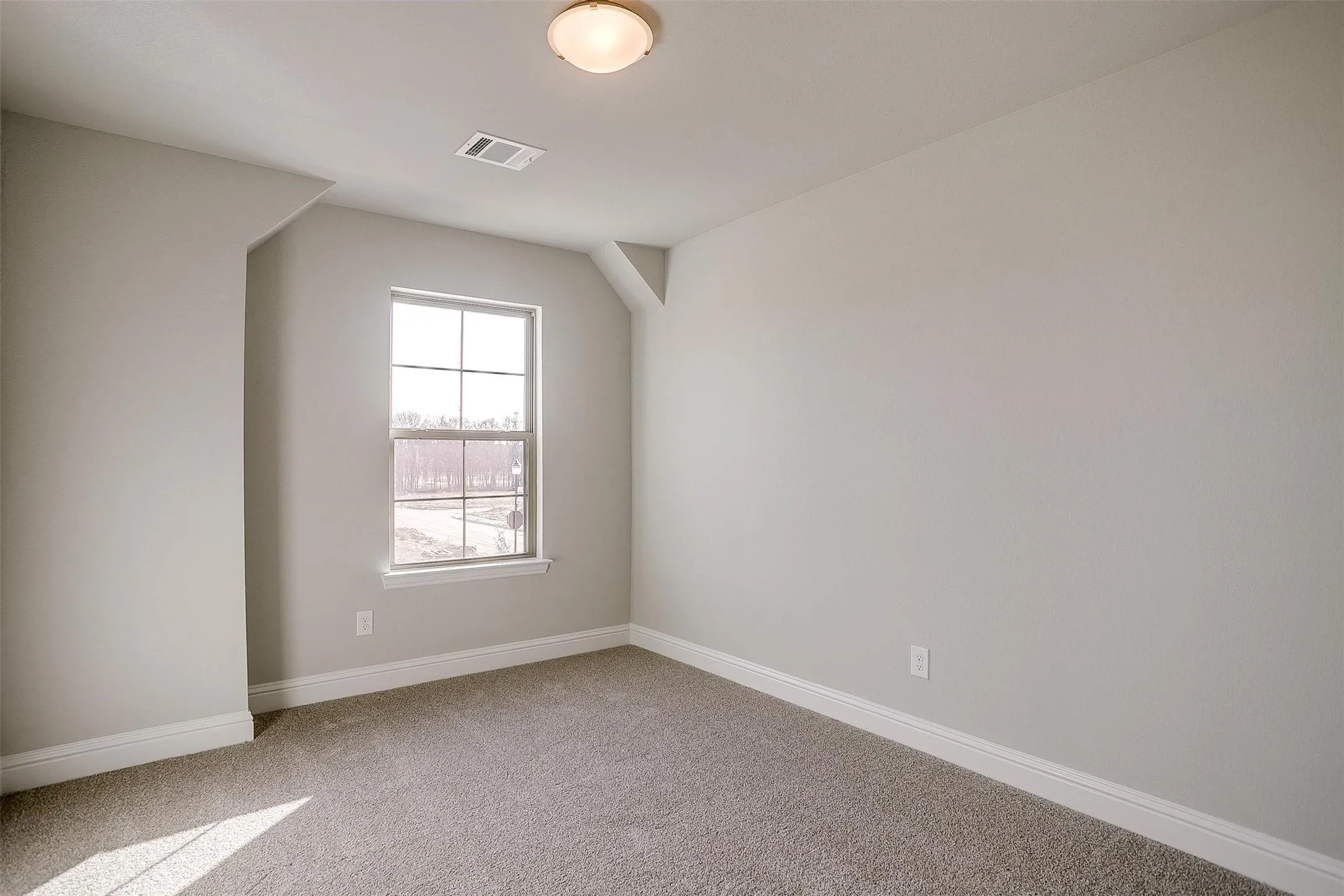Neutral paint palette, carpeted flooring, large window with grid pattern, overhead flush-mount lighting, and white trim