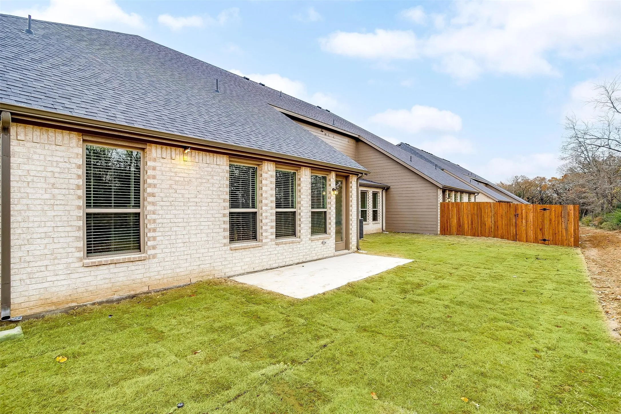 Expansive backyard featuring a manicured lawn, a concrete patio, and a new wooden fence