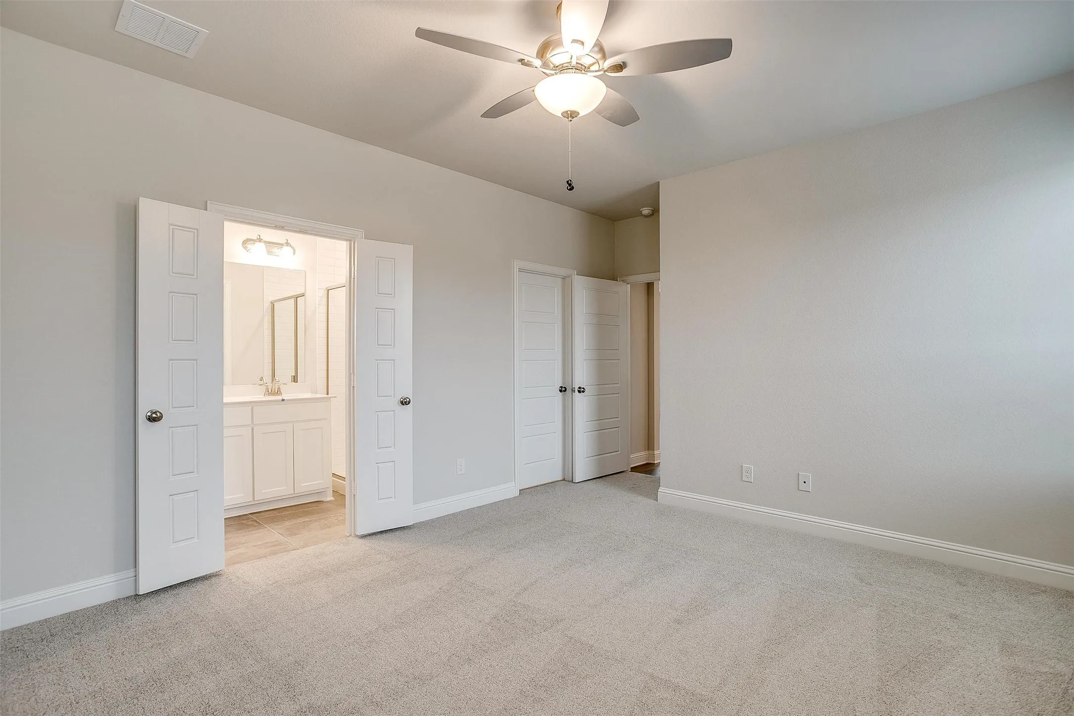 Light gray carpeting with white baseboards, a ceiling fan with integrated lighting, and white paneled doors