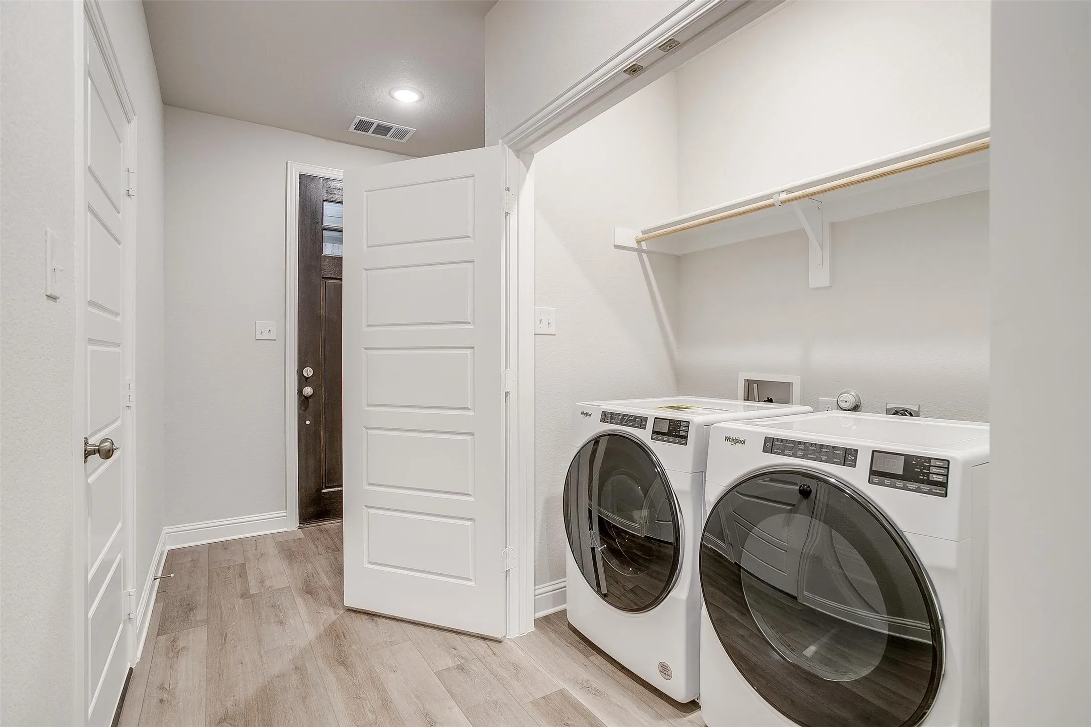 Laundry area with built-in shelving and wood-finish flooring