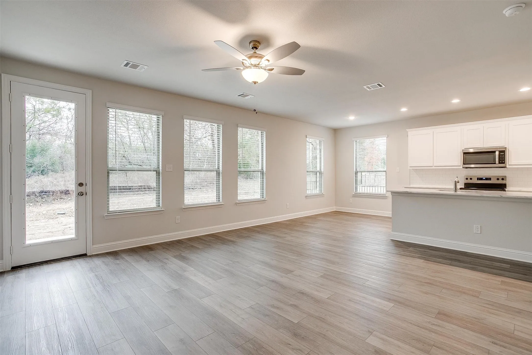 Open-concept living area featuring wood-finish flooring, recessed lighting, and a ceiling fan