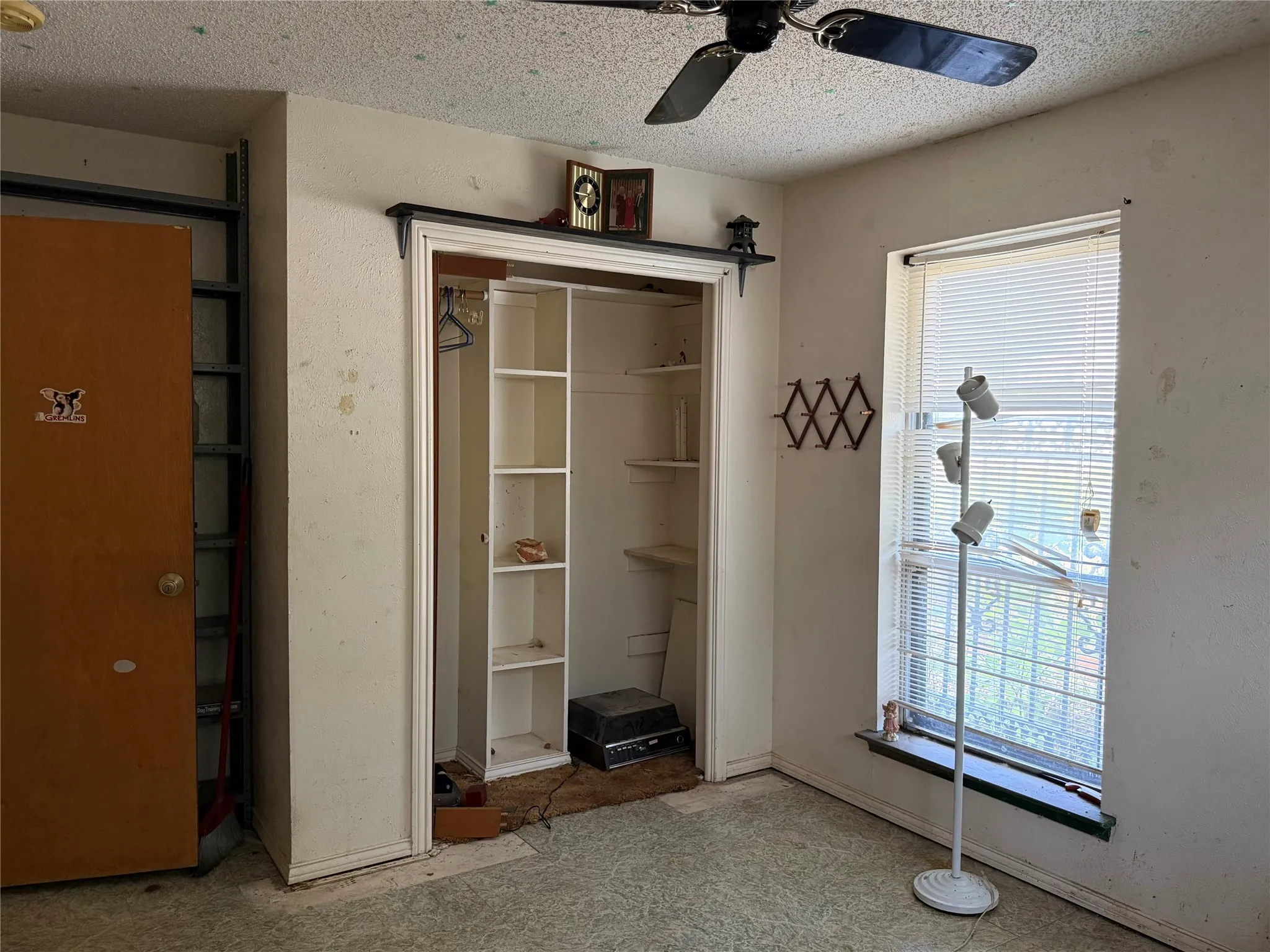 Built-in shelving, window with blinds, ceiling fan, and carpeted flooring