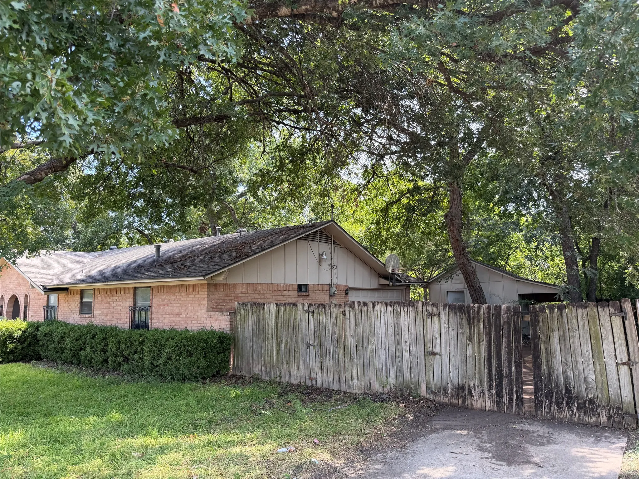 Brick exterior with a gabled roofline, complemented by mature trees and a wood fence