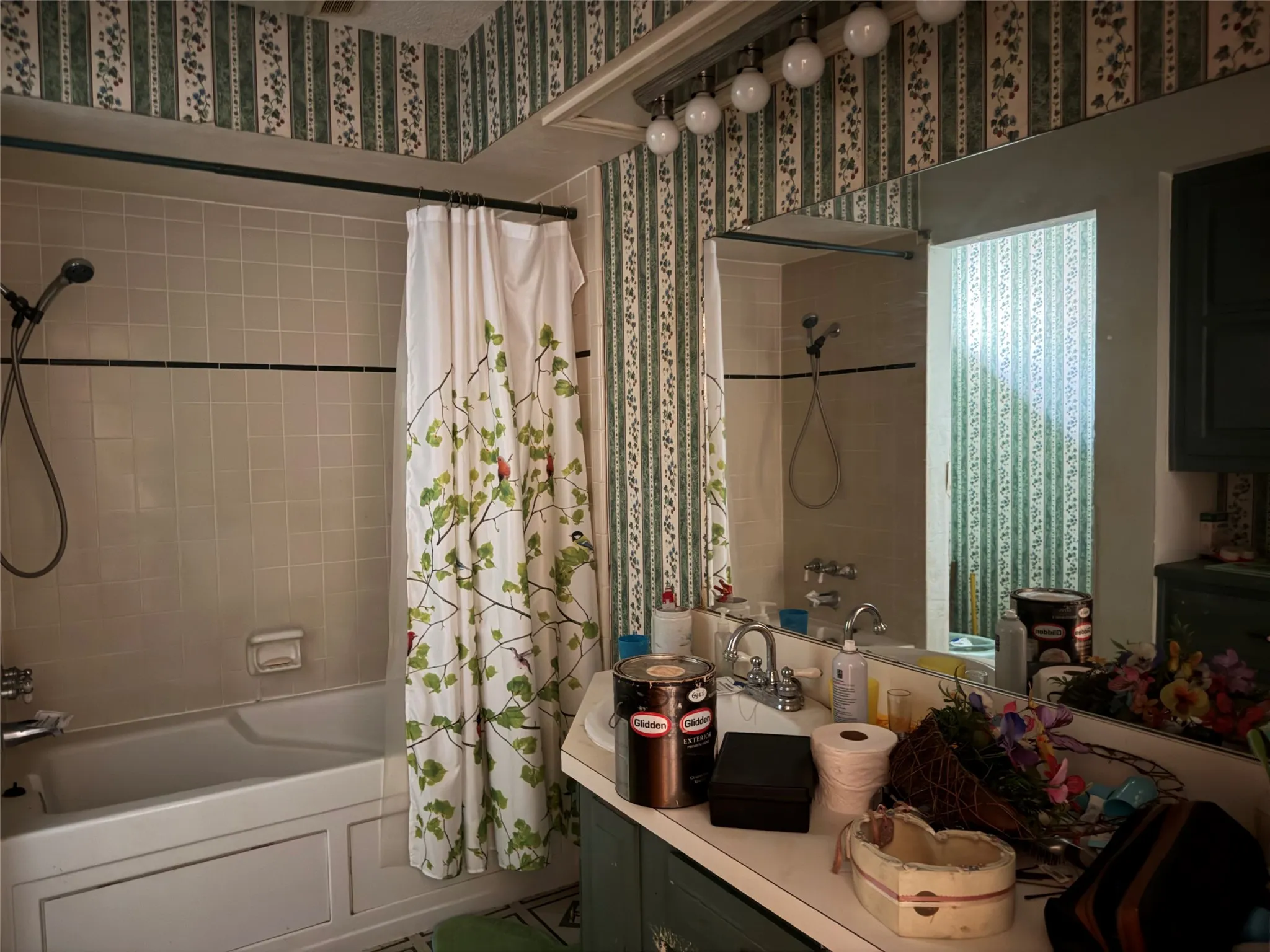 Built-in bathtub with shower, tiled surround, vanity with integrated sink, and wall-mounted mirror