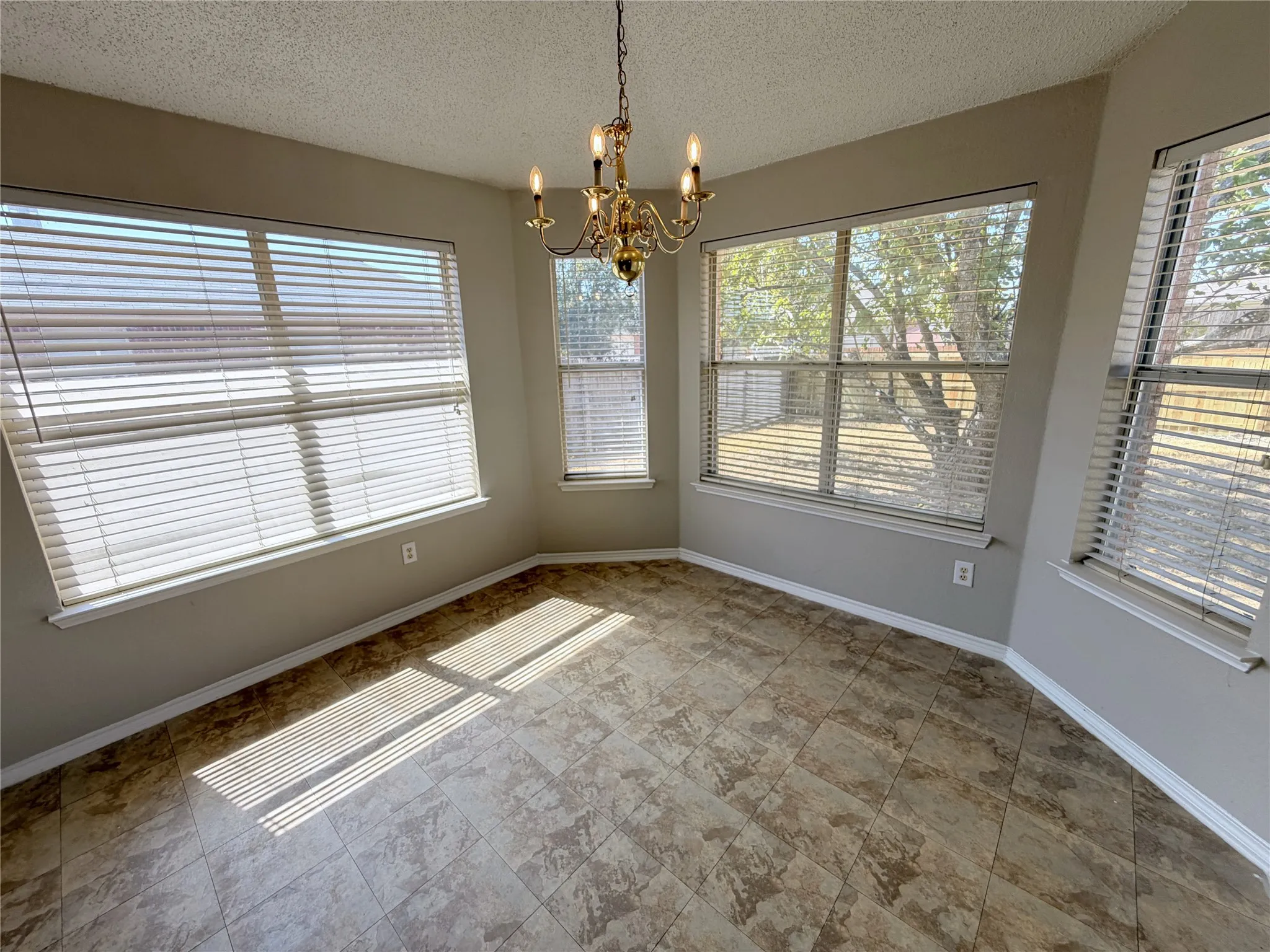 Bay window design with multiple windows, durable tile flooring, and a brass-finish chandelier
