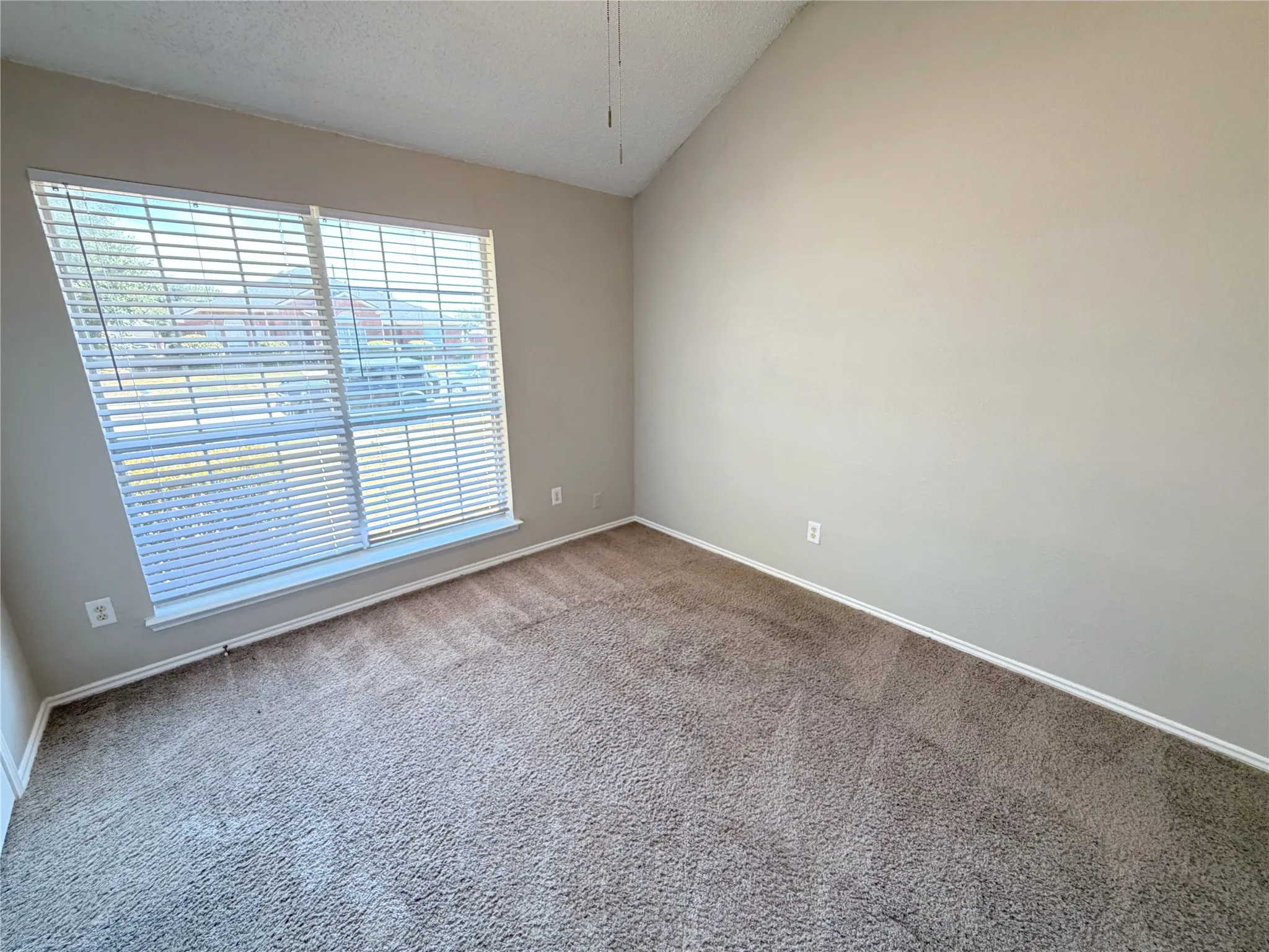 Vaulted ceiling with a ceiling fan, carpet flooring, and window blinds