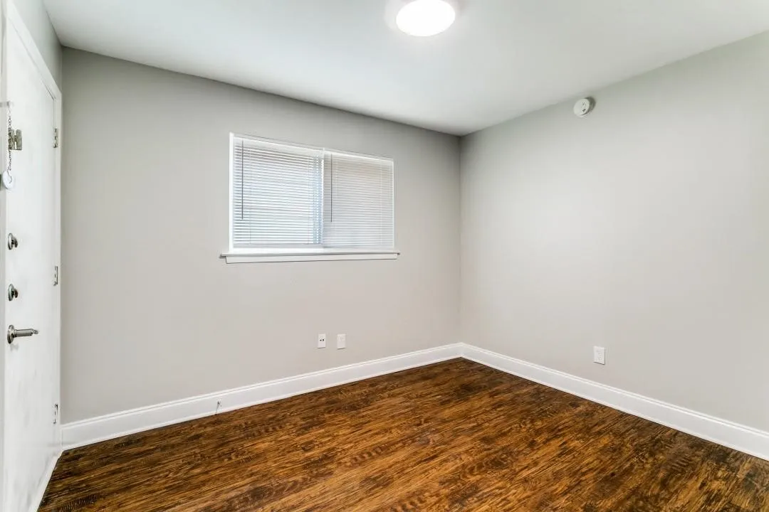Wood-finish flooring, white window blinds, and a flush-mount ceiling light