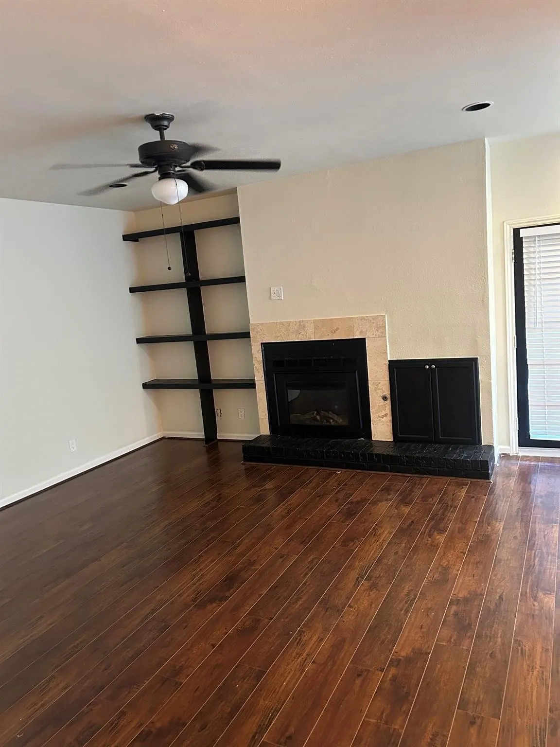 Wood-finish flooring, ceiling fan, built-in shelving, fireplace with stone surround, recessed lighting