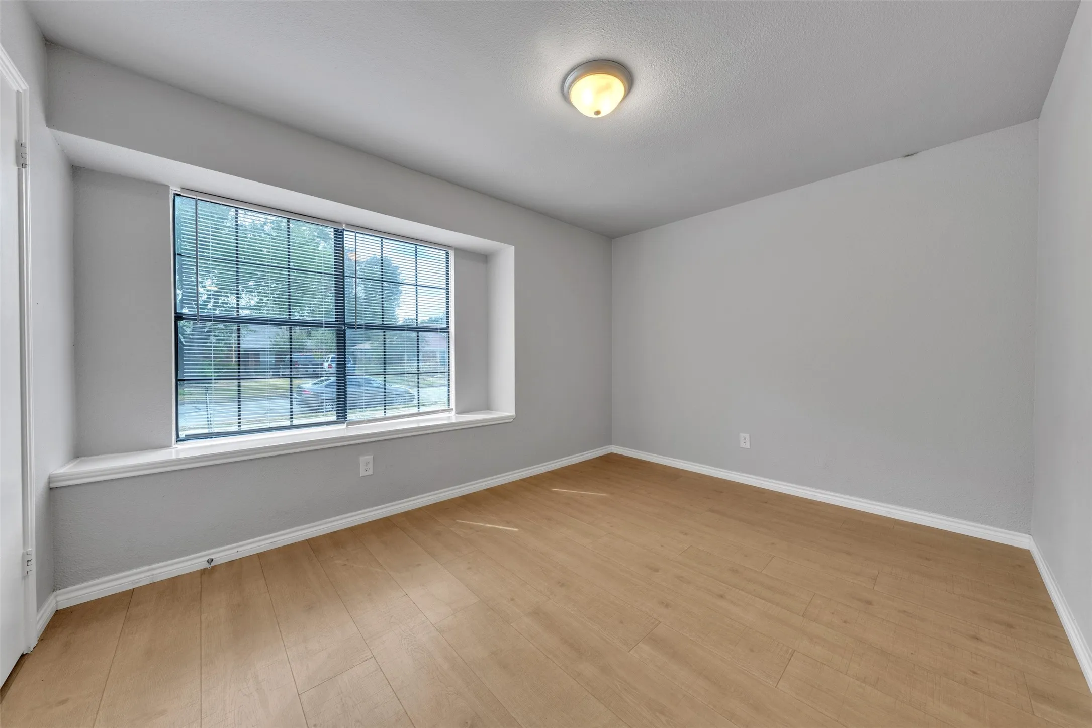 Light wood-finish flooring, neutral wall paint, and a built-in window seat