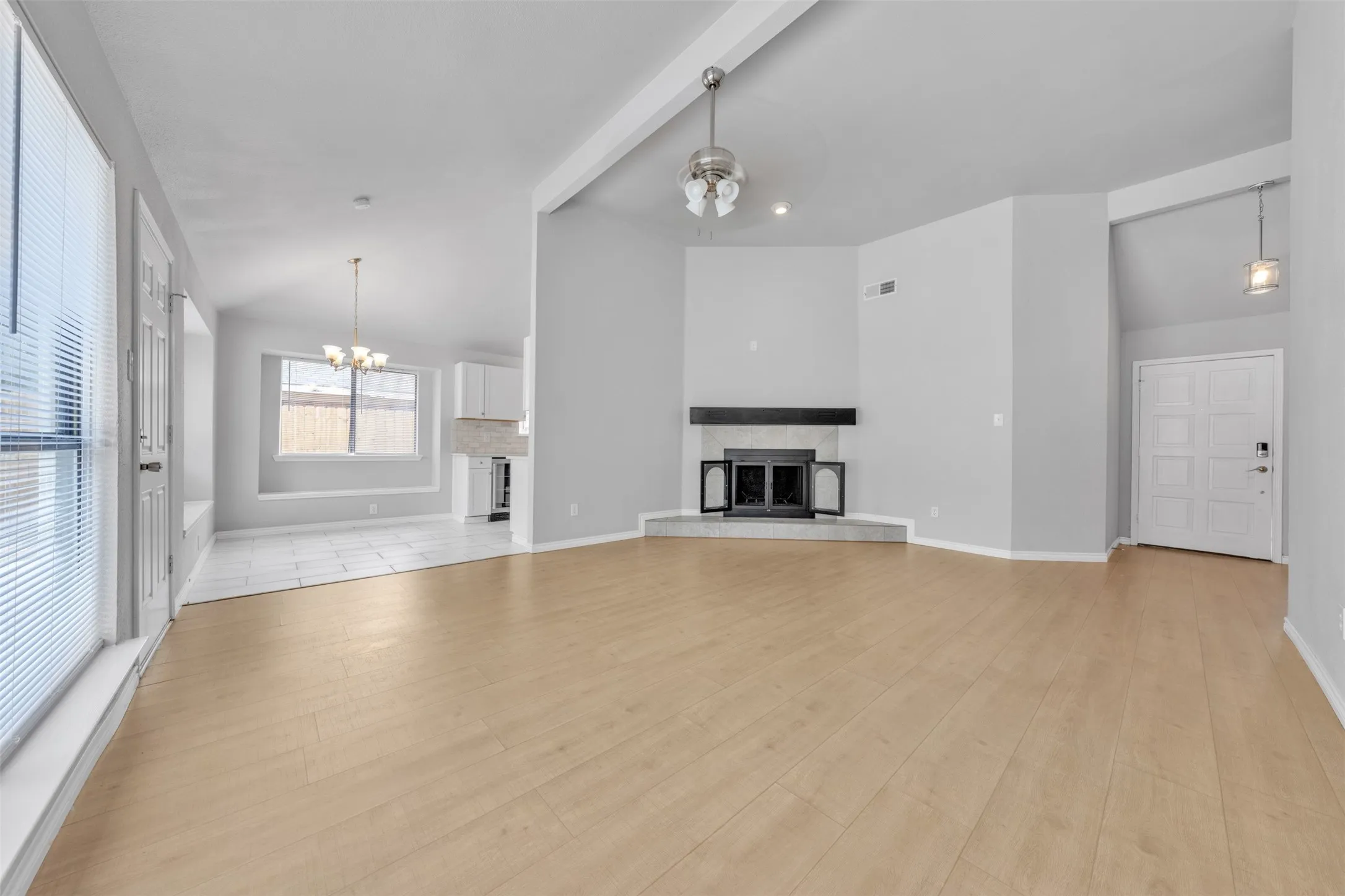 Light wood-finish flooring with a corner fireplace featuring a dark wood mantel and a tile hearth