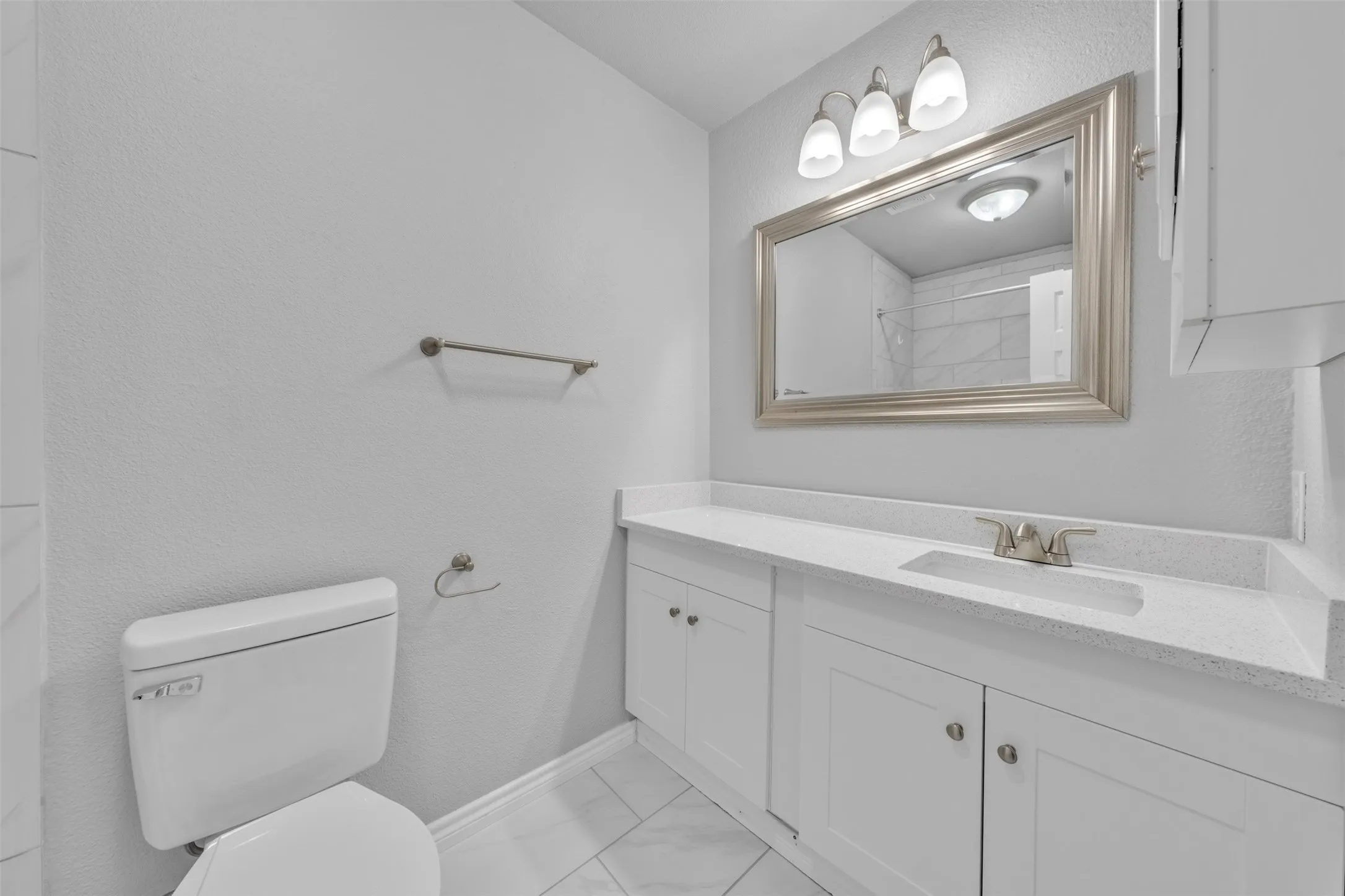 Vanity with an integrated sink, brushed nickel faucet, and a framed mirror