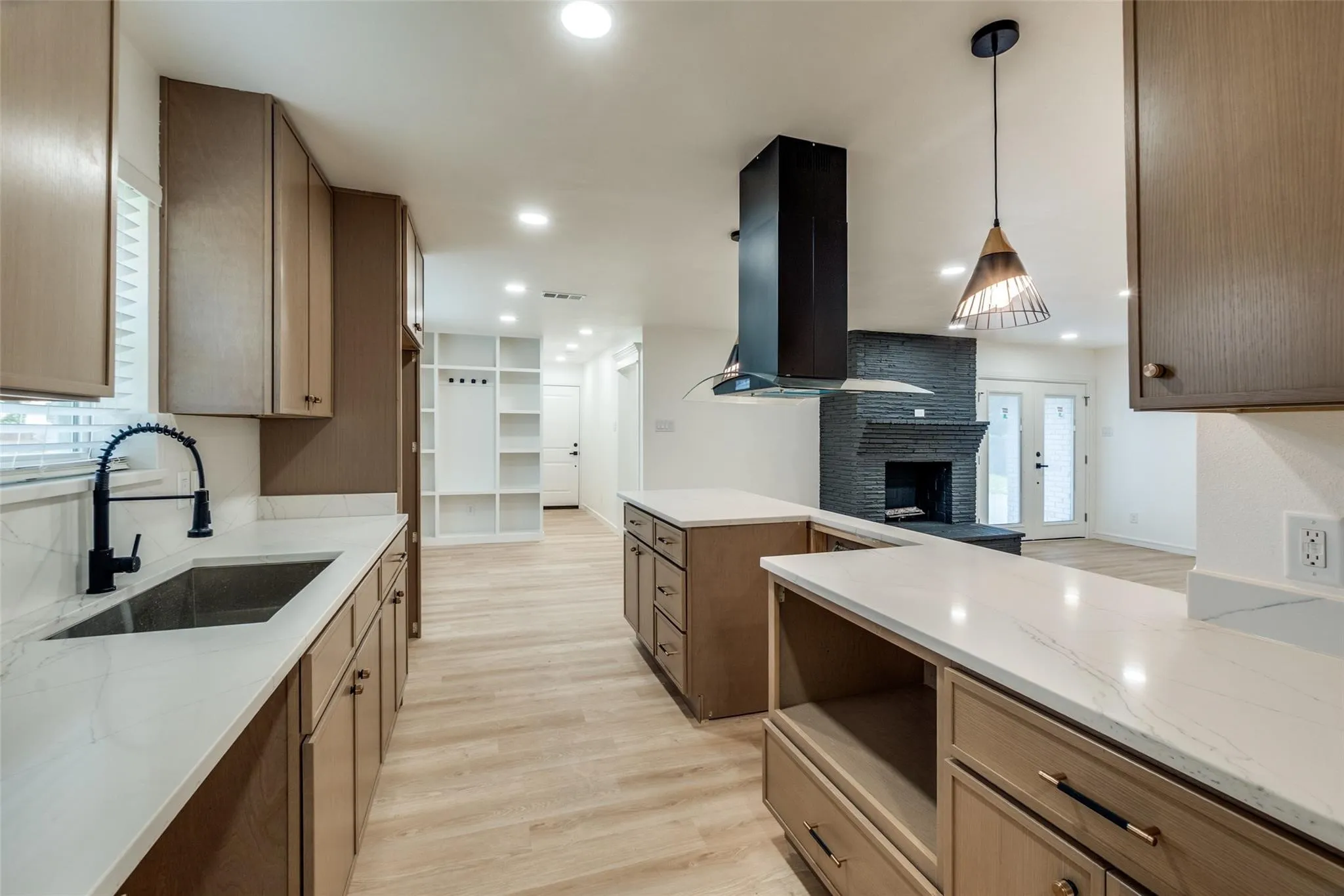 Kitchen featuring wood-finish cabinetry, white countertops, stainless steel undermount sink with a matte black faucet, and pendant lighting