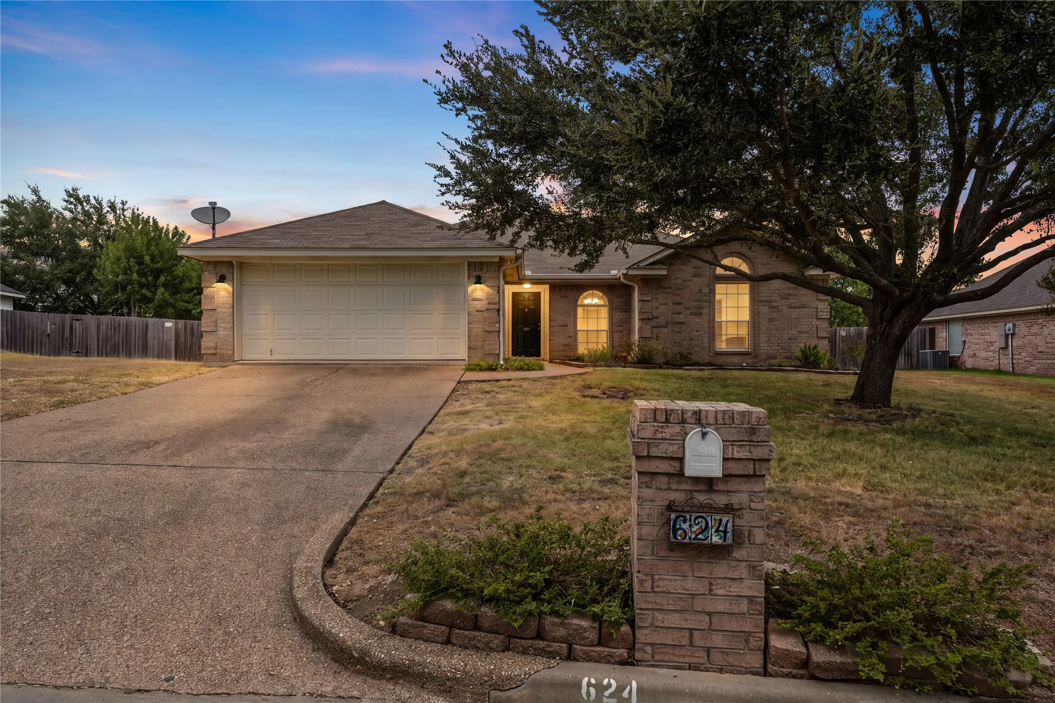 Brick exterior with arched window accents, attached two-car garage, and a concrete driveway