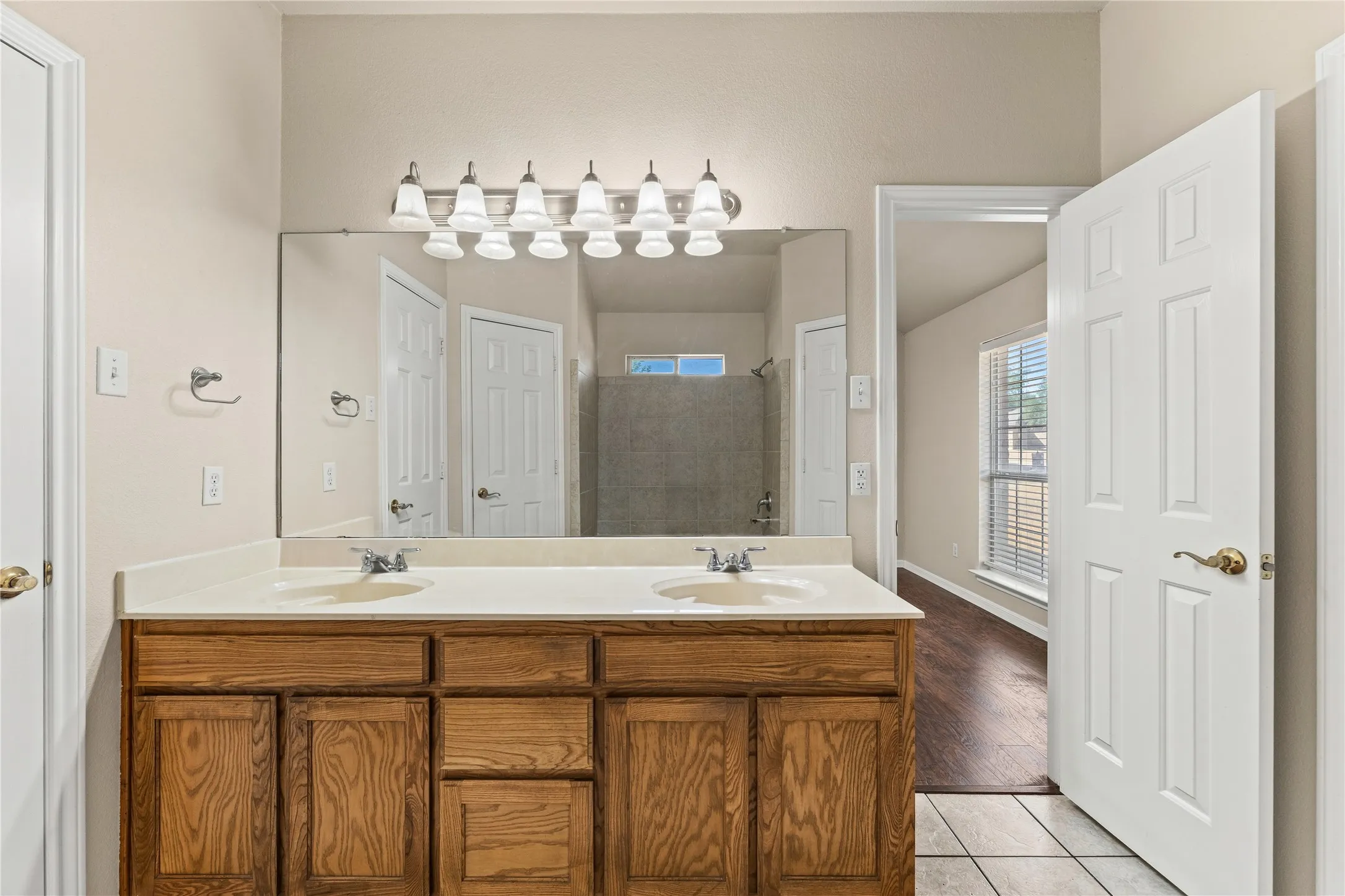 Double vanity with light wood-finish cabinetry, white countertop, and dual undermount sinks
