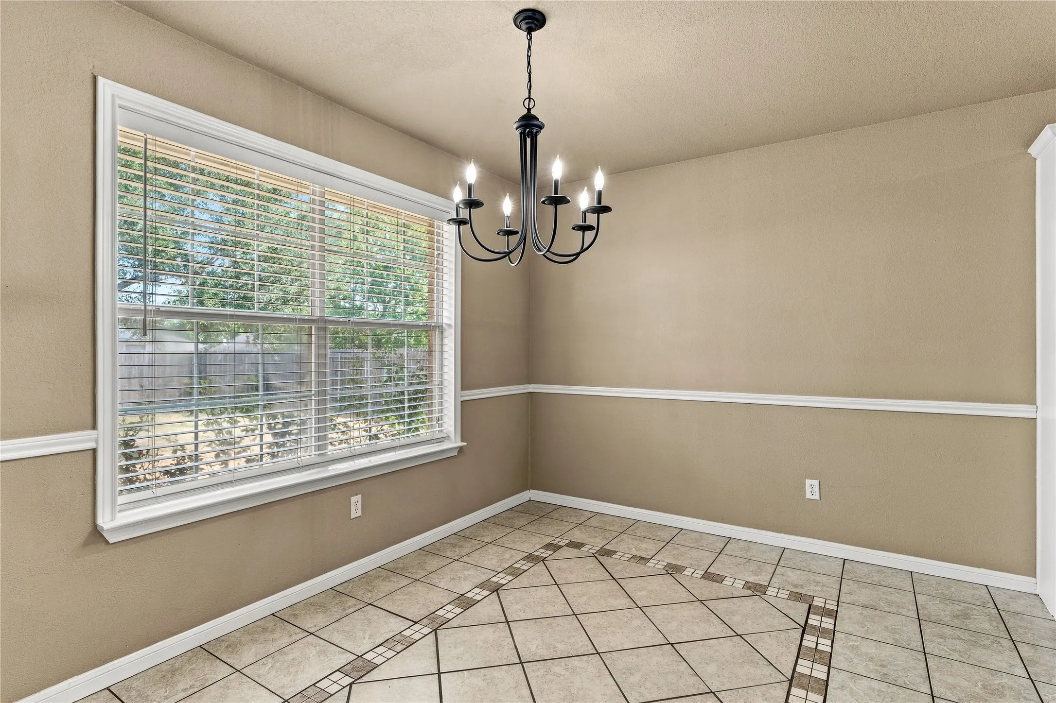 Tile flooring with a decorative inlay pattern, white trim, and a multi-pane window