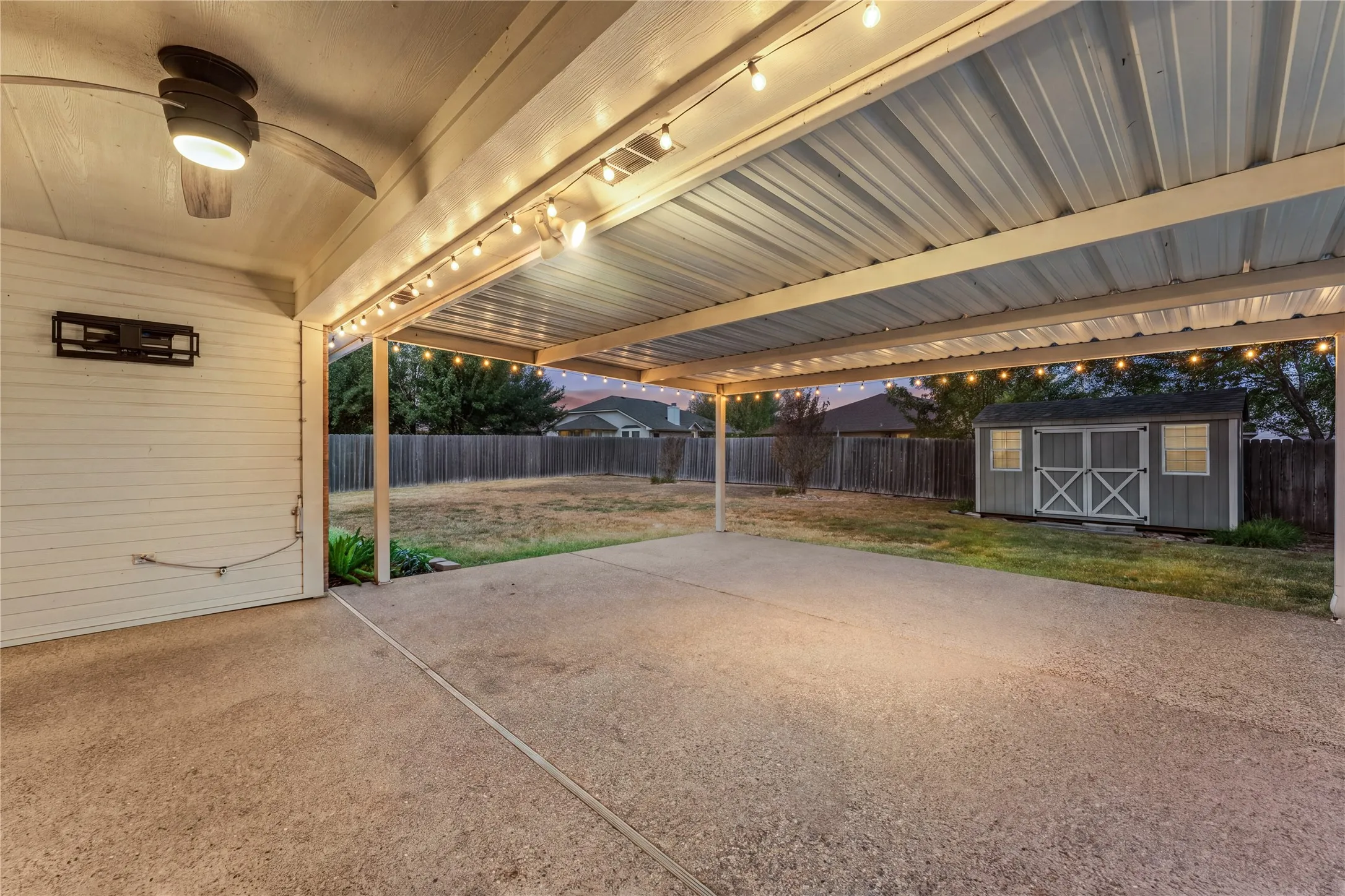 Expansive covered patio with concrete flooring, string lighting, and a ceiling fan
