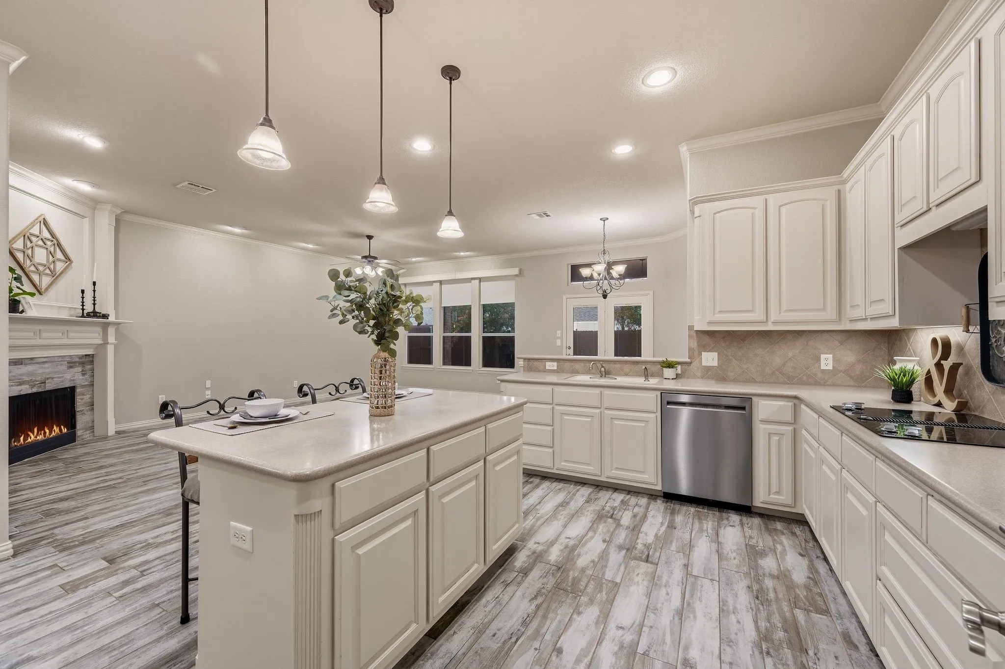 Kitchen island with countertop seating, wood-finish flooring, electric fireplace with stone surround, recessed lighting, and stainless steel appliances