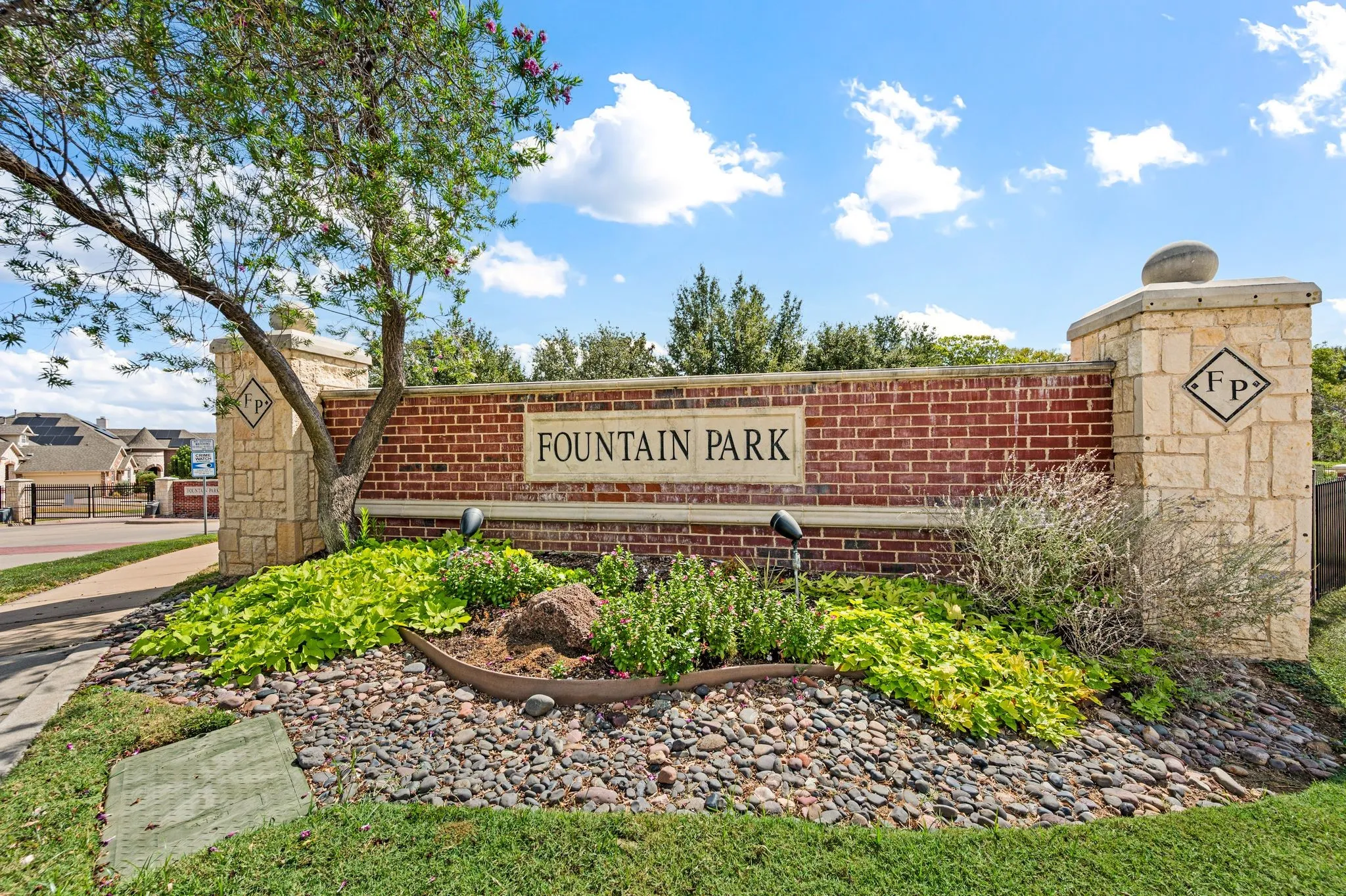 Brick and stone entry monument featuring landscaping with varied plantings and ground cover, and a decorative rock bed