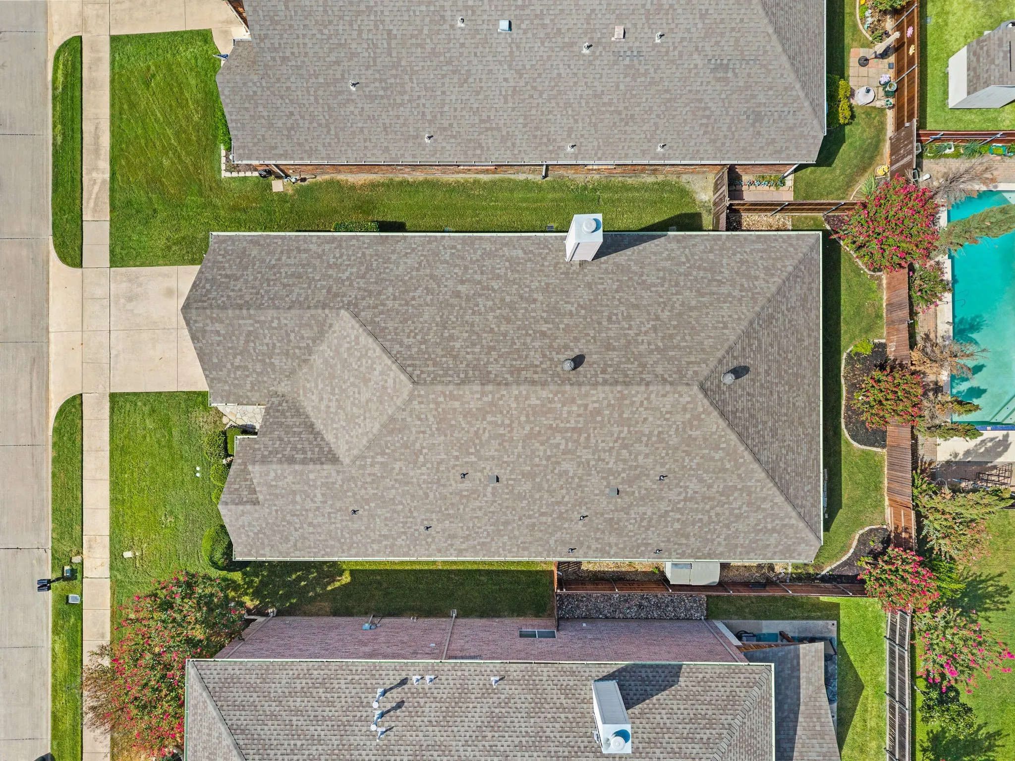 Gable roof with asphalt shingles, concrete driveway, and manicured lawn