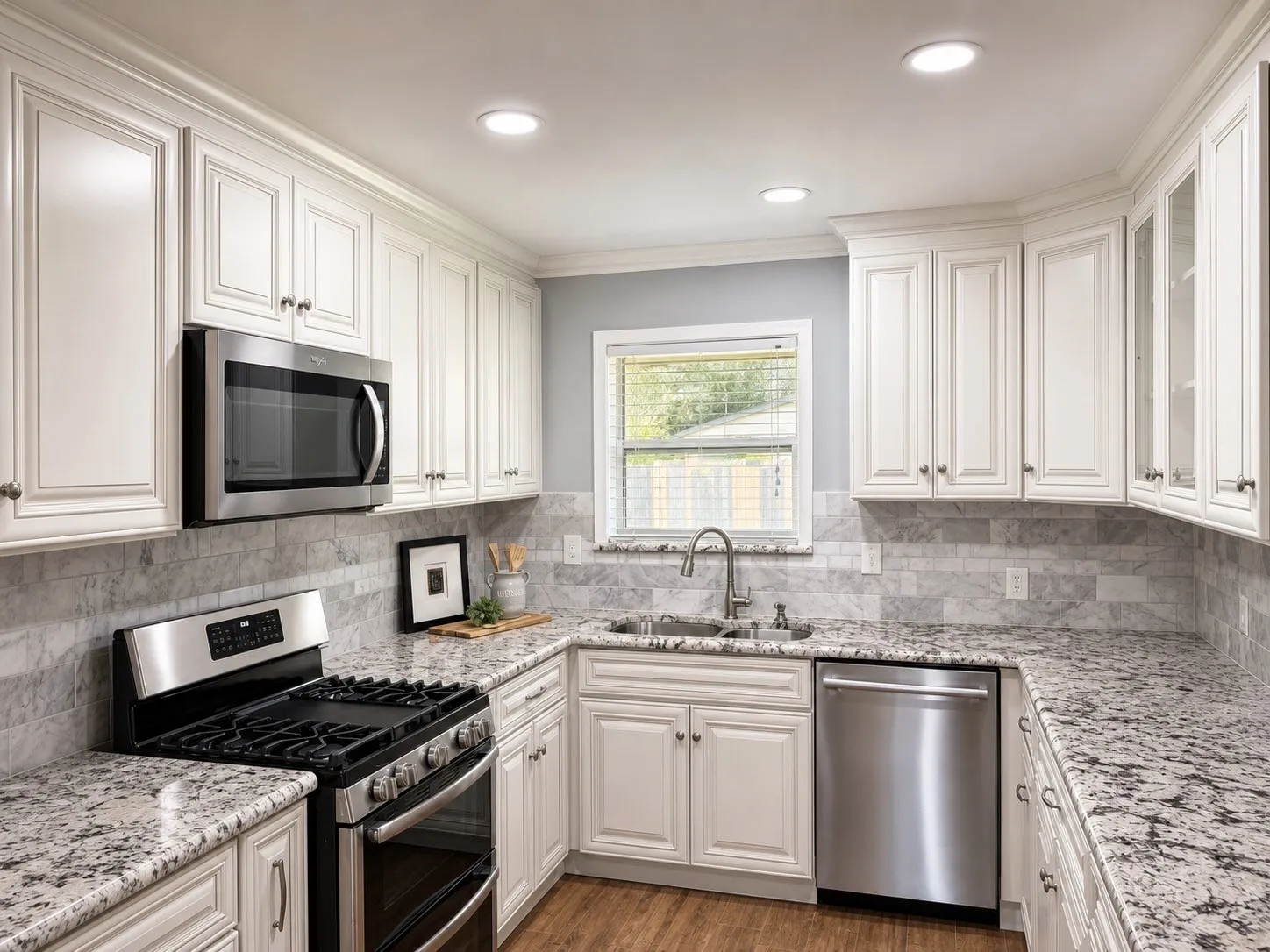 White cabinetry, granite countertops, stainless steel appliances, tile backsplash, and wood-finish flooring