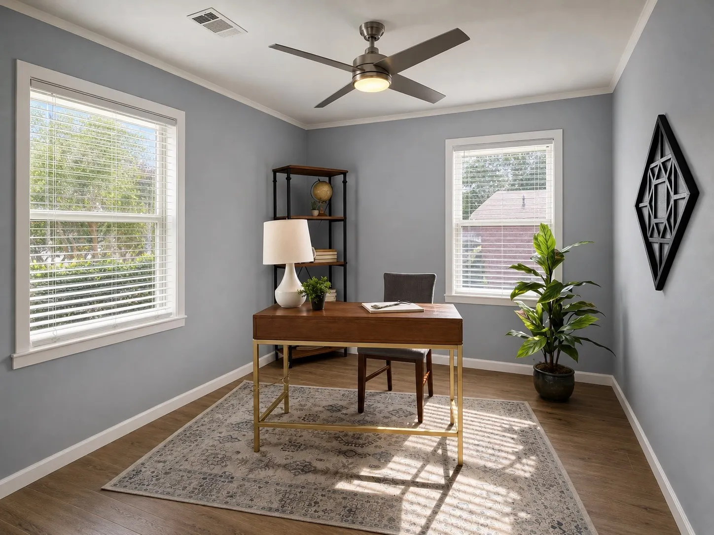 Wood-finish flooring, white crown molding, two windows with blinds, and a ceiling fan with integrated lighting