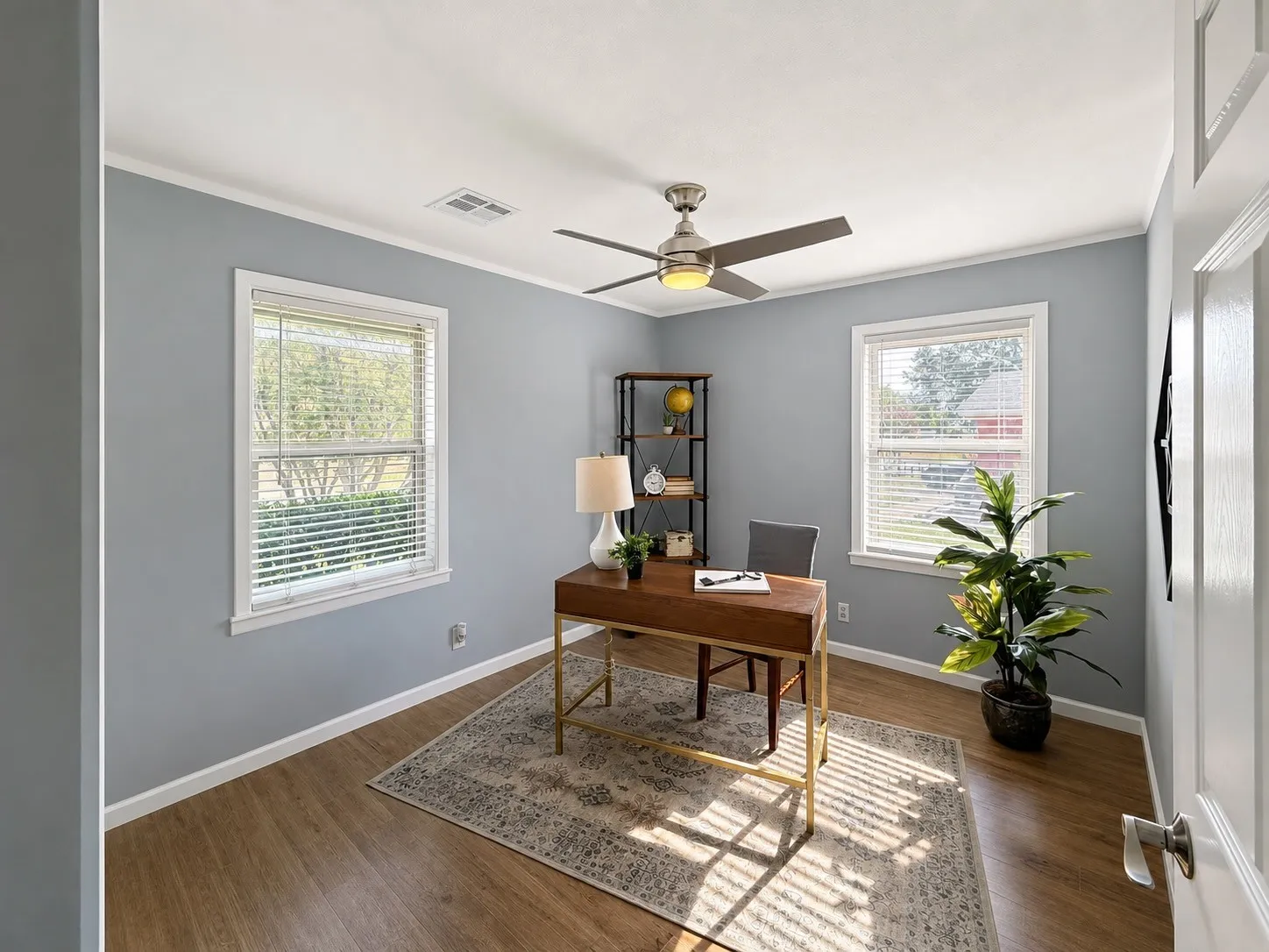 Room featuring wood-finish flooring, two windows with blinds, a ceiling fan with integrated lighting, and crown molding