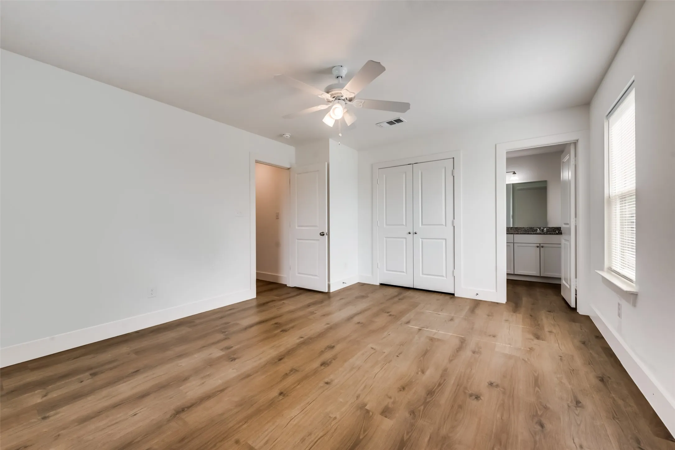Expansive room featuring wood-finish flooring, white walls, built-in closet, ceiling fan, and recessed lighting