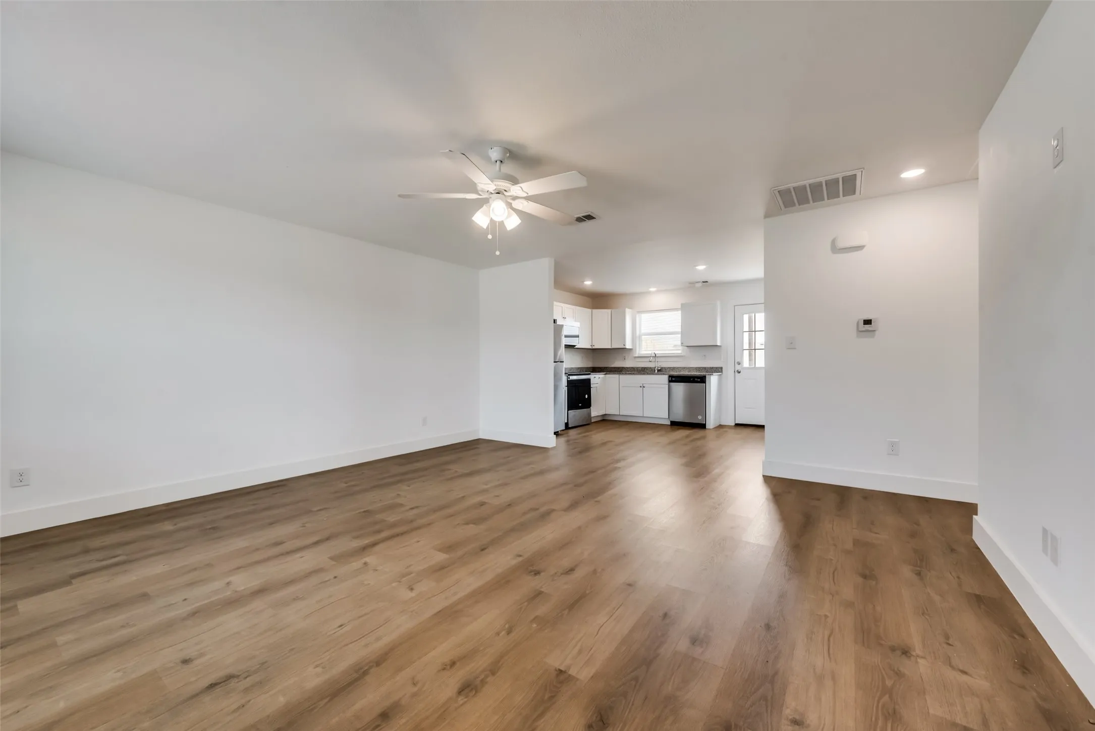 Open concept living area with wood-finish flooring, recessed lighting, and a ceiling fan