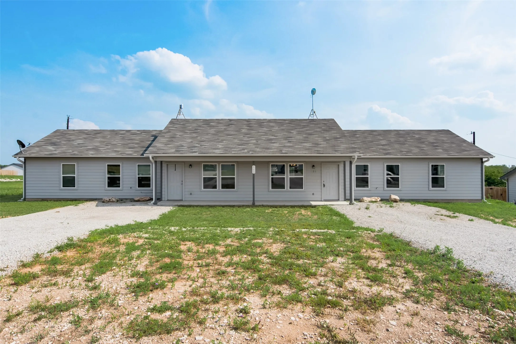 Duplex structure with gray siding and individual gravel driveways