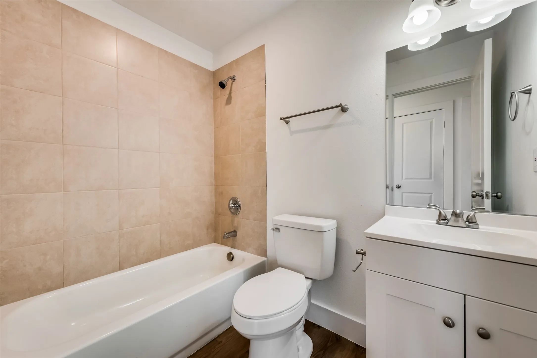 White vanity with chrome hardware, countertop with integrated sink, and wall-mounted mirror